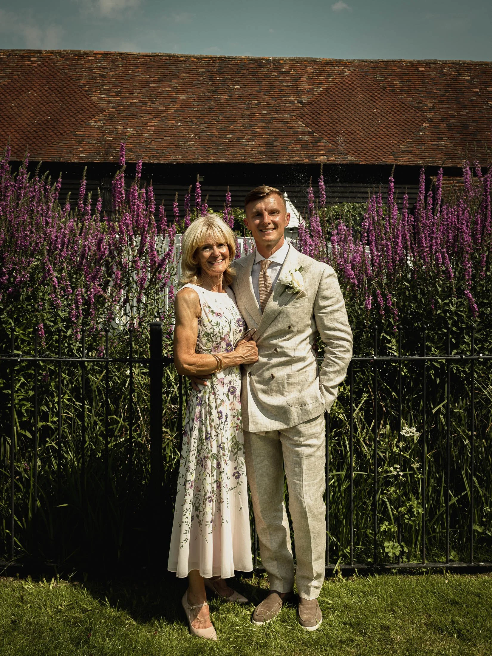 A group portrait in the gardens of Winters Barns, showing the groom standing with his mother.