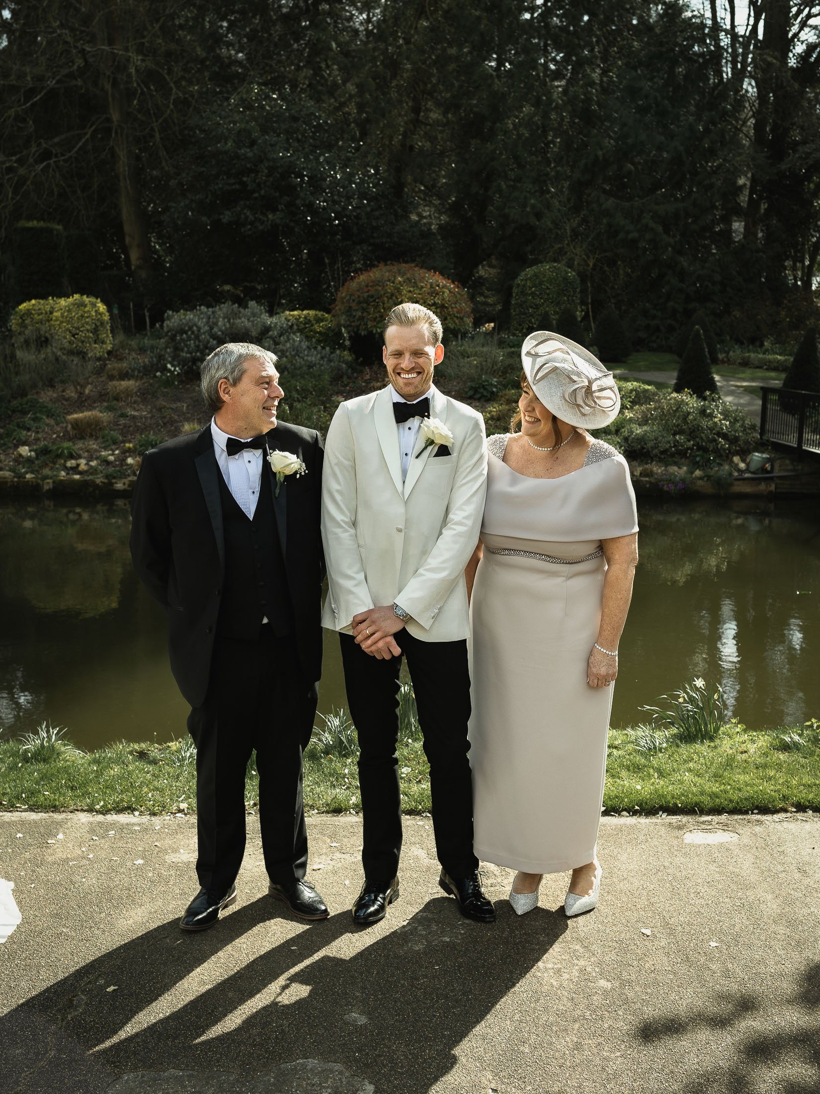 Formal group shot of a groom in white tuxedo with his parents at The Orangery in Maidstone, Kent.