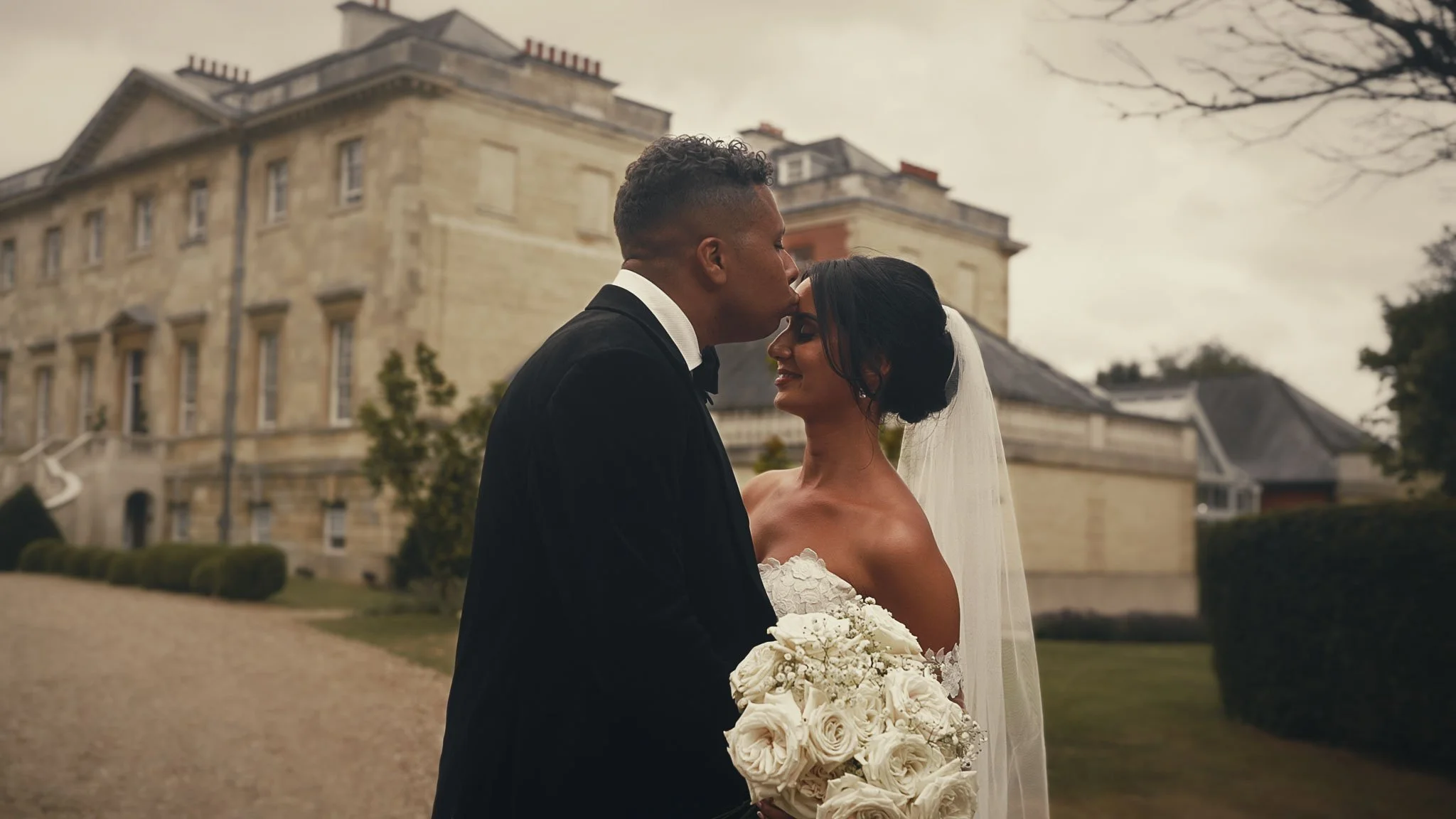 A couple walk together during their black tie summer wedding film at Botleys Mansion in Surrey