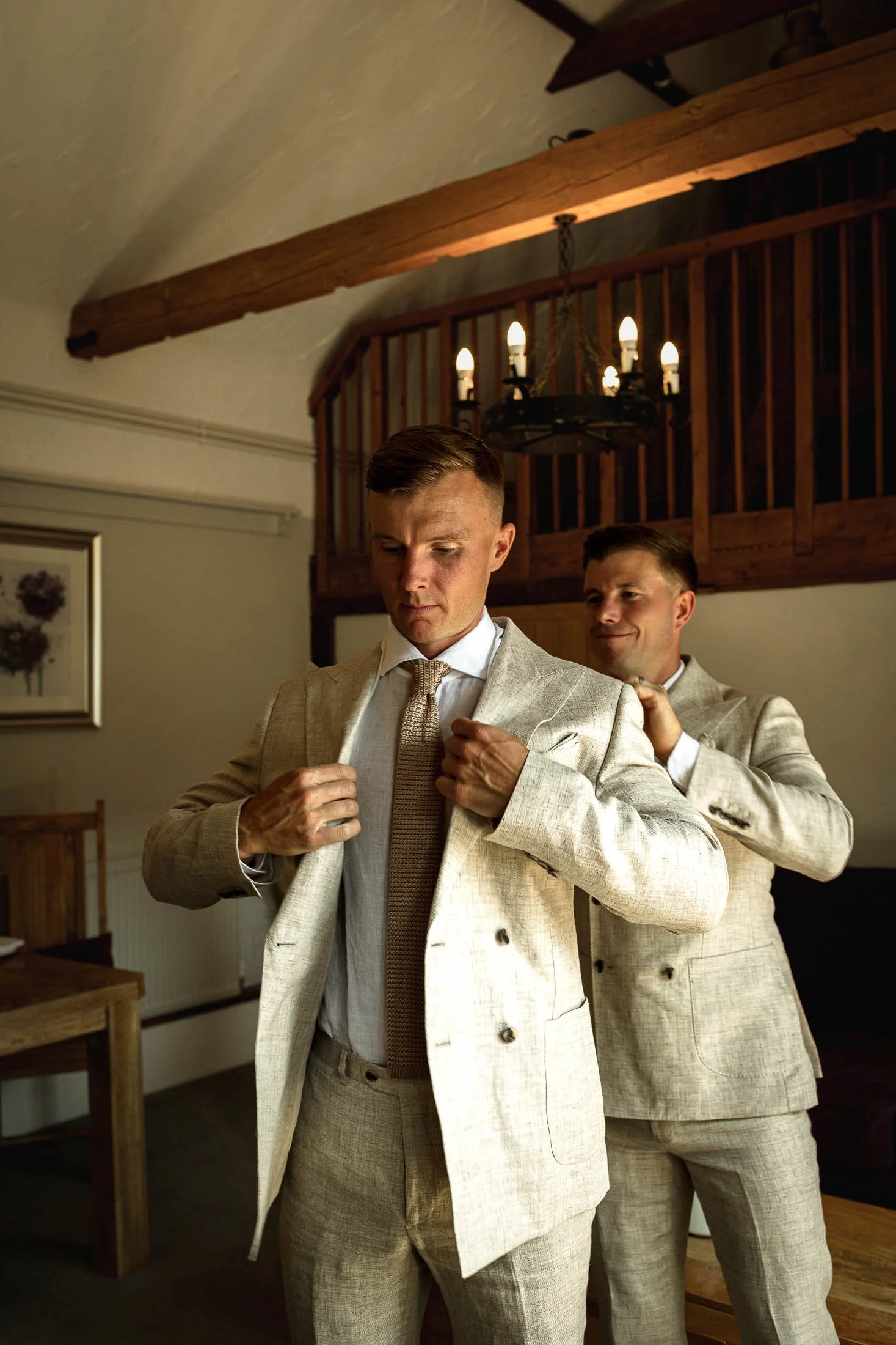 A candid moment during groom preparations at Winters Barns as the Groom is helped by the Best Man to put on his jacket.
