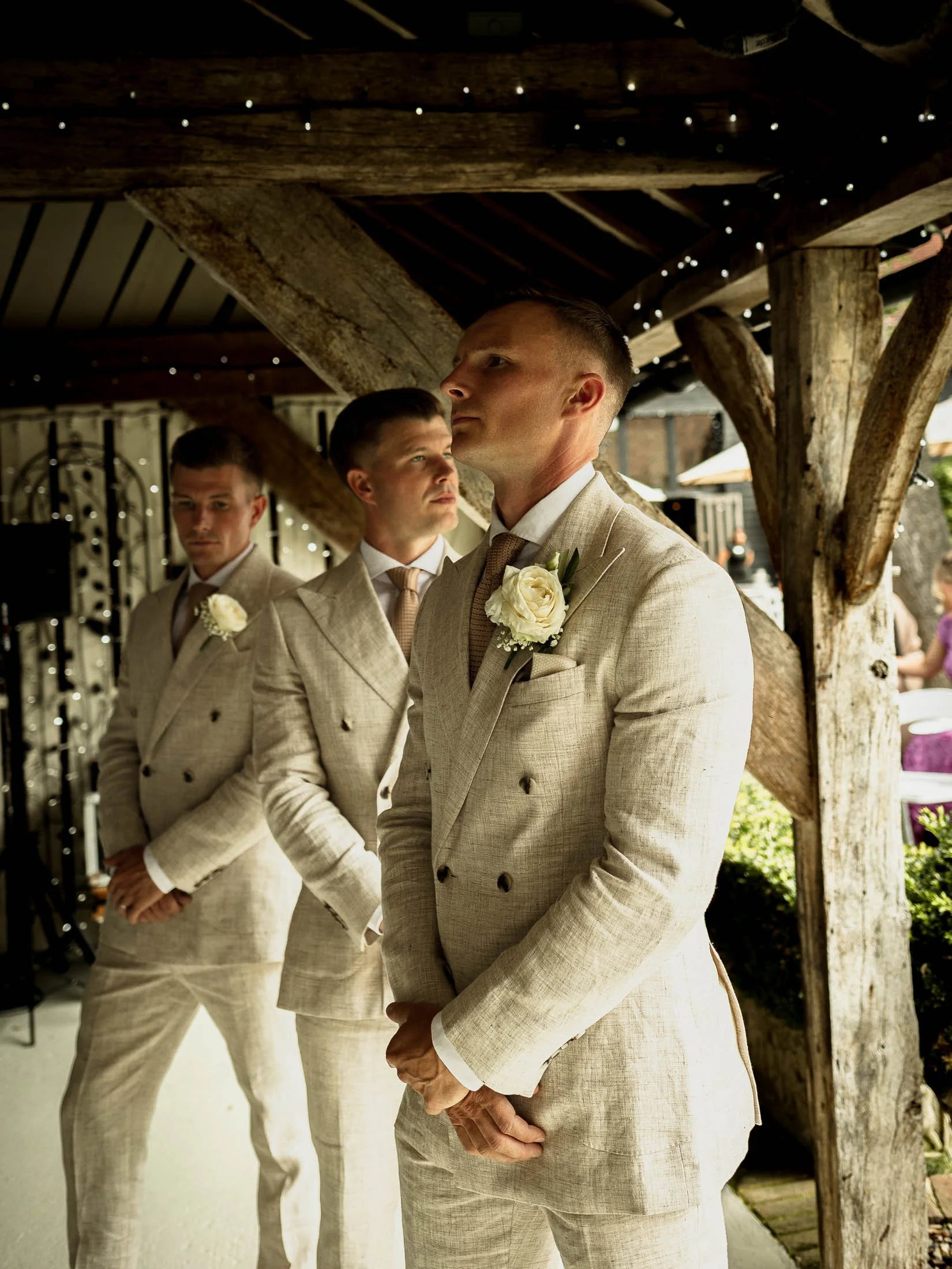 A groom waits at the end of the aisle for his bride at the beginning of their summer outdoor wedding ceremony at Winters Barns.