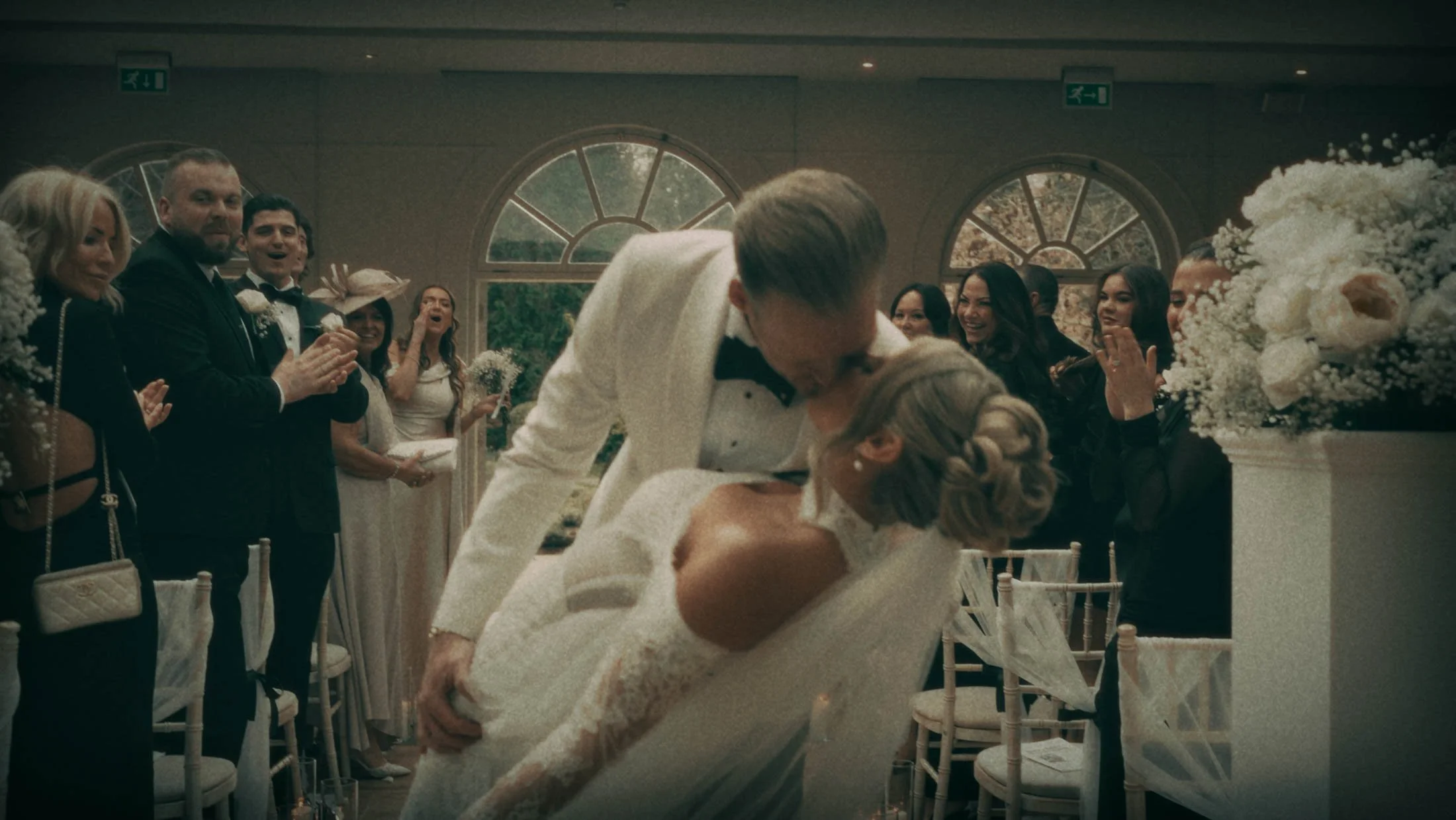 A groom dips and kisses his bride as they exit their indoor ceremony at their Orangery Maidstone wedding, an iconic moment from their storytelling wedding film in the UK.