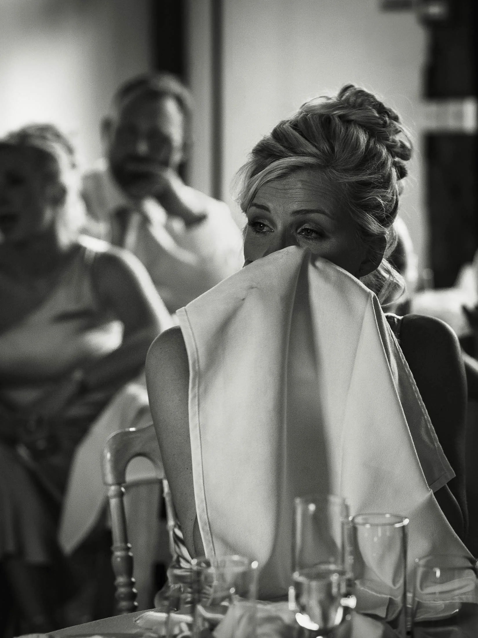 A bridesmaid uses a napkin to wipe tears from her eyes during emotional speeches at a Winters Barns wedding in Kent.