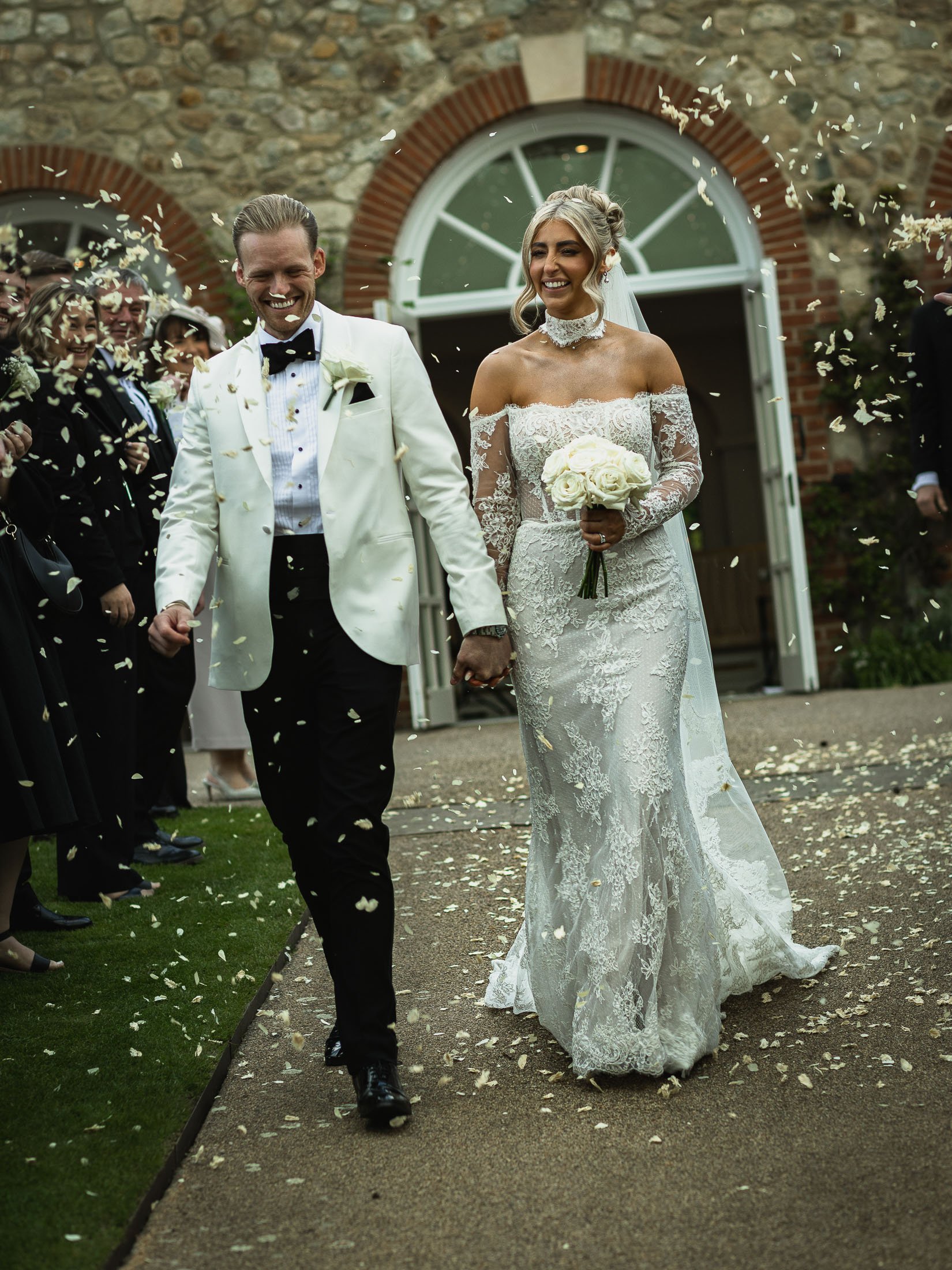 Editorial wedding photography and videography at The Orangery Maidstone with a couple walking through confetti and laughing.