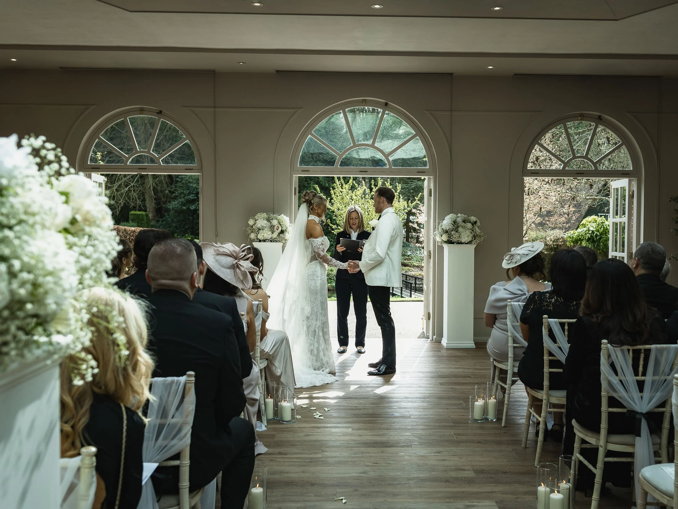 Bride and groom stand together during their indoor wedding ceremony at The Orangery Maidstone in Kent.