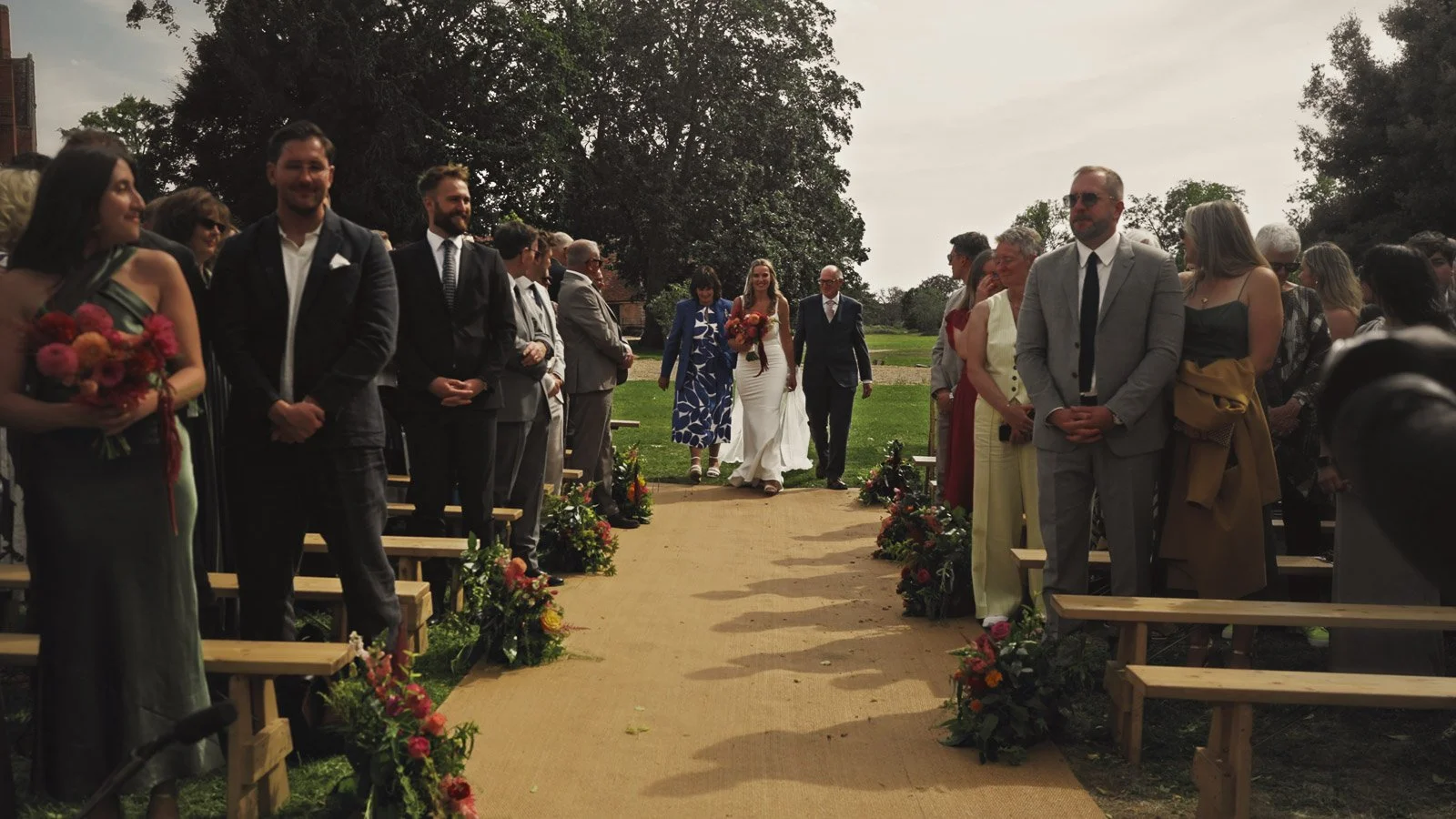 A bride enters and walks down the aisle at her outdoor colourful riverside wedding ceremony on the banks of the River Thames.