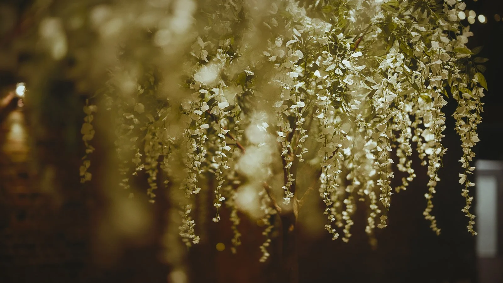 Low hanging florals and trees decorate the Tithe Barn at Cooling Castle Barn for a wedding reception.