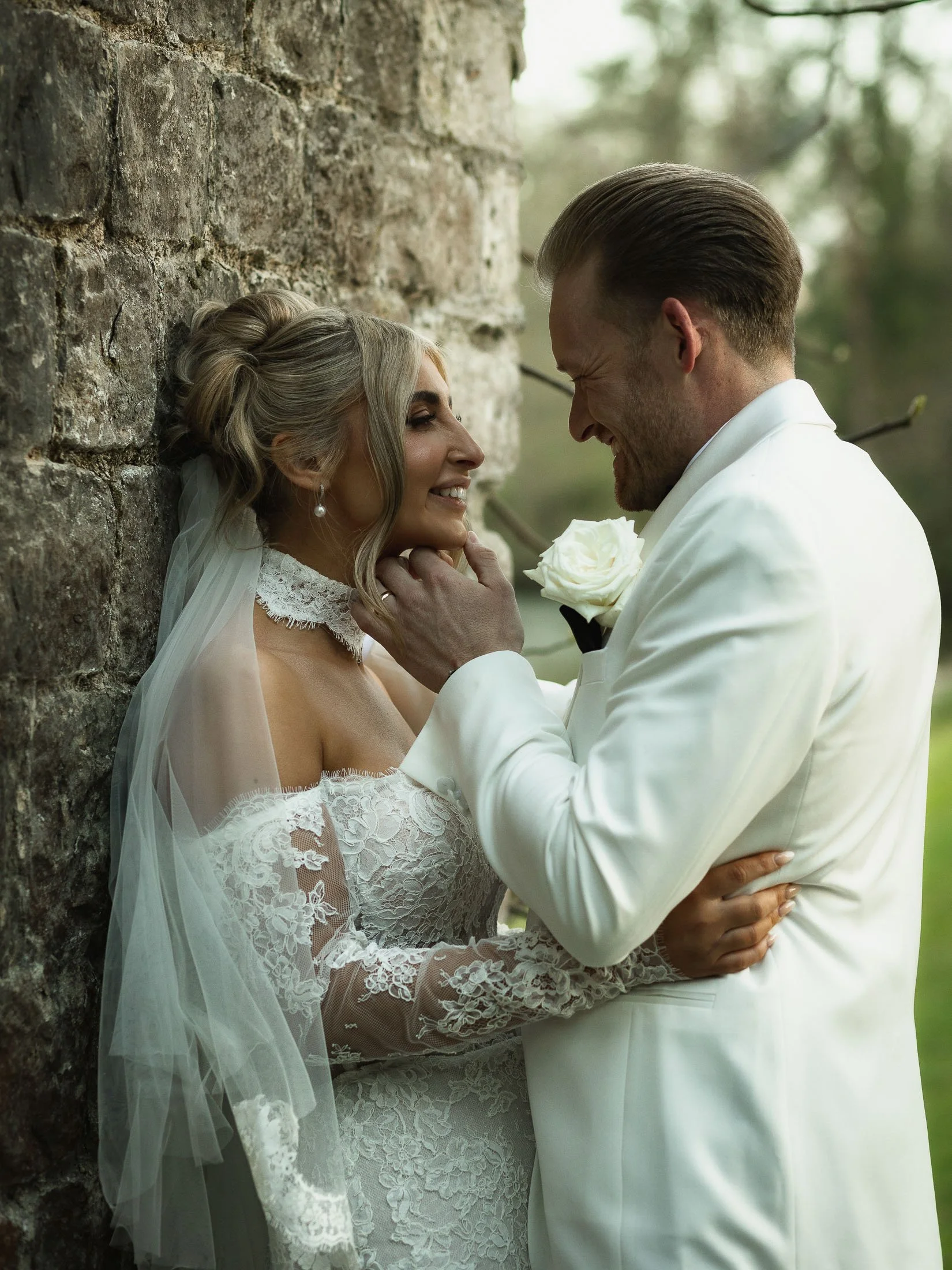 Editorial wedding photography and videography at The Orangery Maidstone as a groom holds the chin of his bride and smiles.