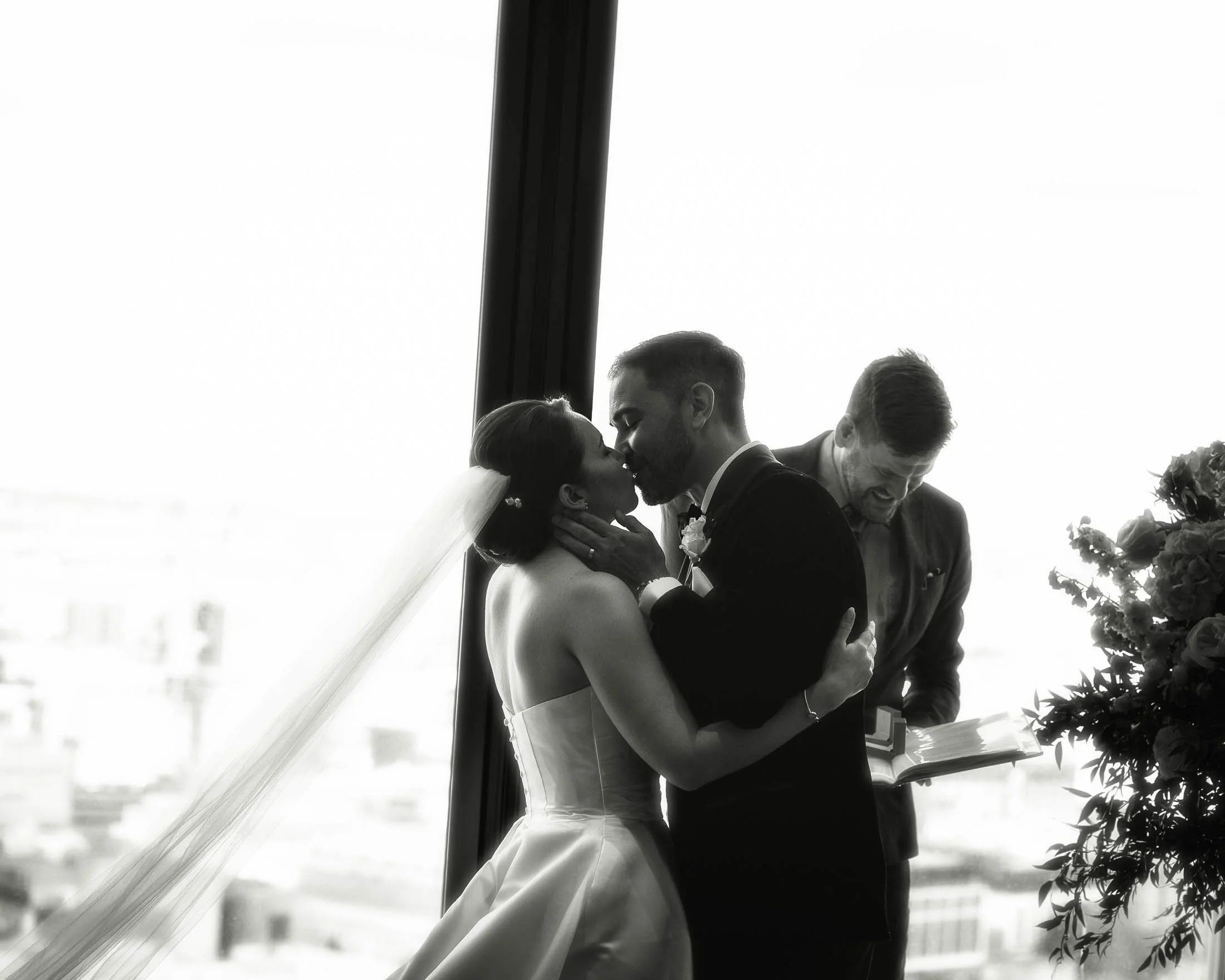 A bride and groom share their first kiss during their indoor London wedding ceremony.