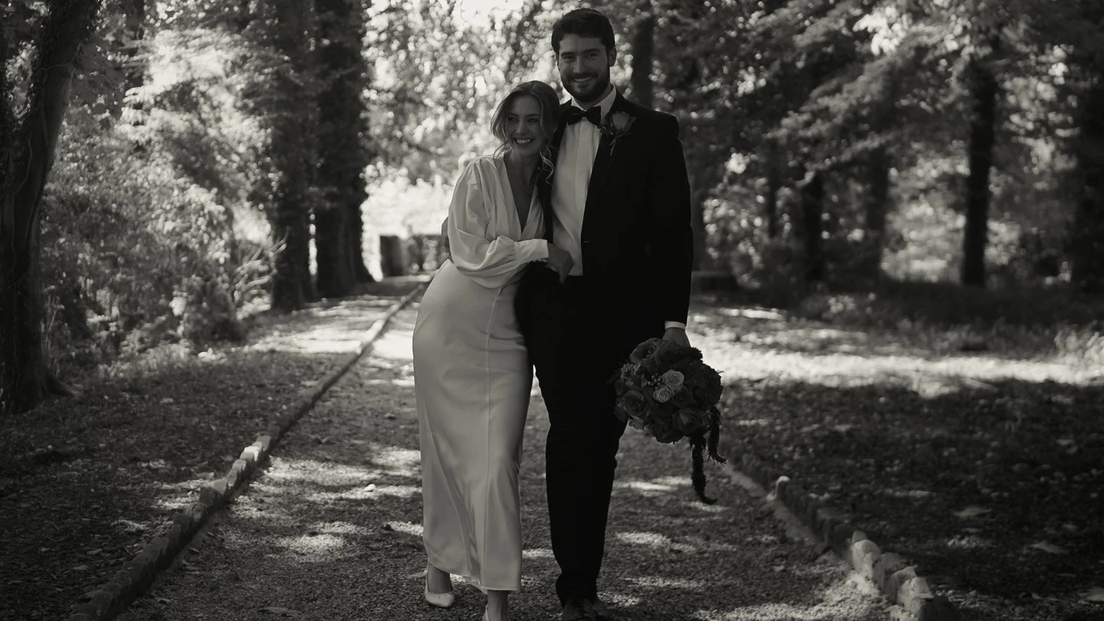 A couple walking together through woodland in a timeless fine art wedding film moment.