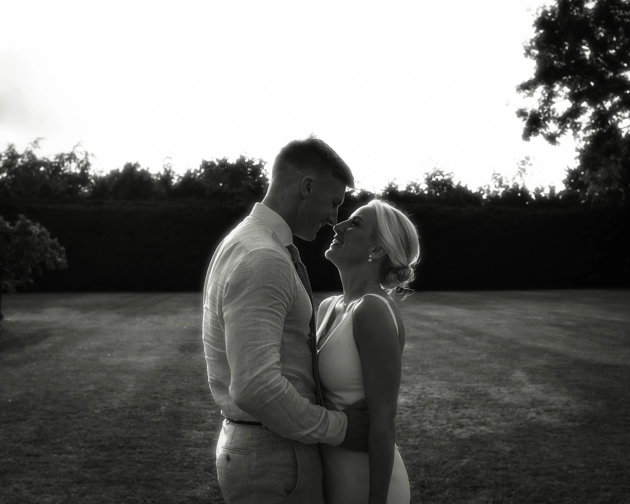 A classic and timeless black and white wedding photograph of a bride and groom at sunset during their summer wedding day at Winters Barns, Kent, UK.