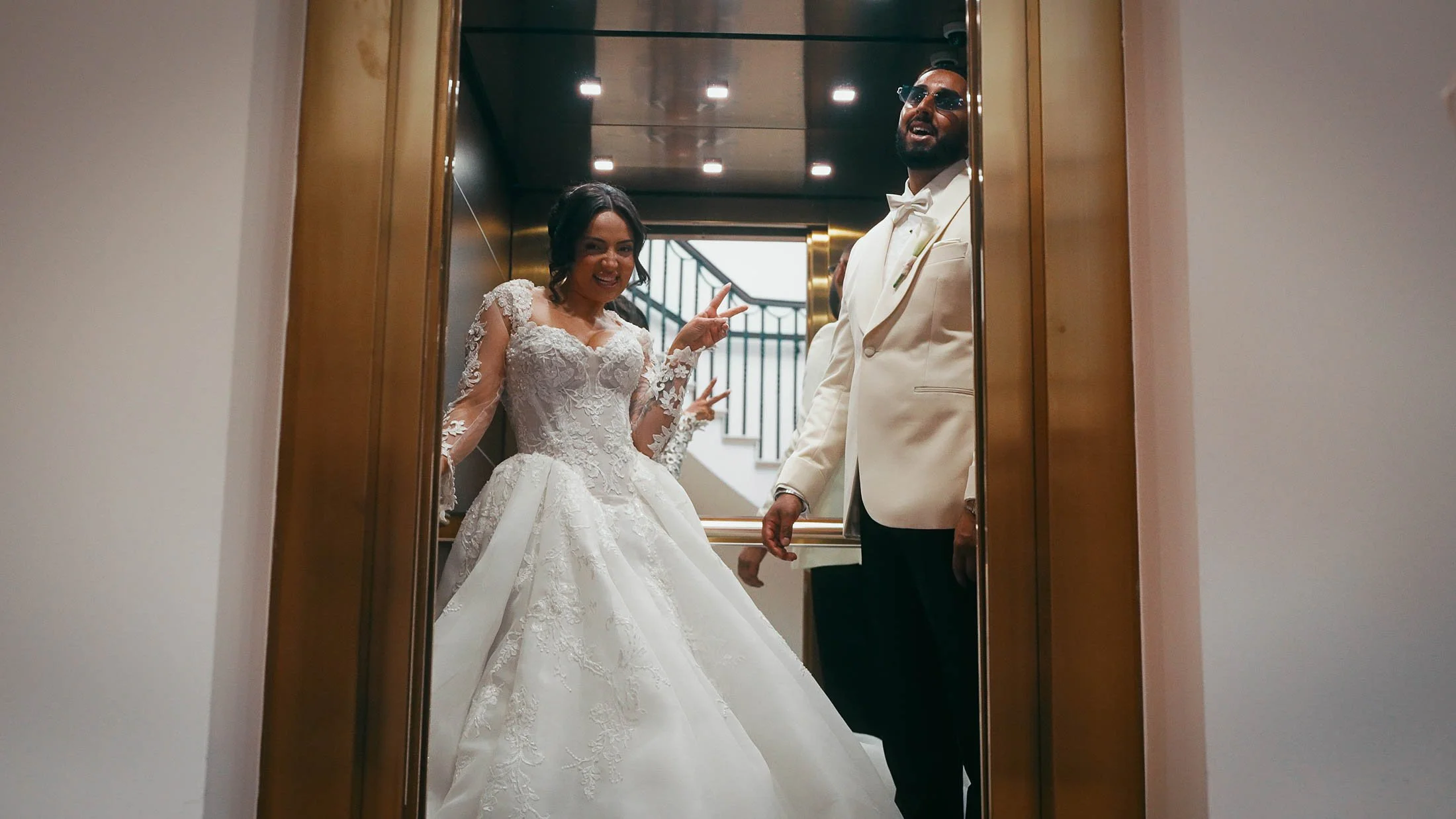 A bride and groom laugh together in a golden elevator at Grantley Hall on their wedding day.