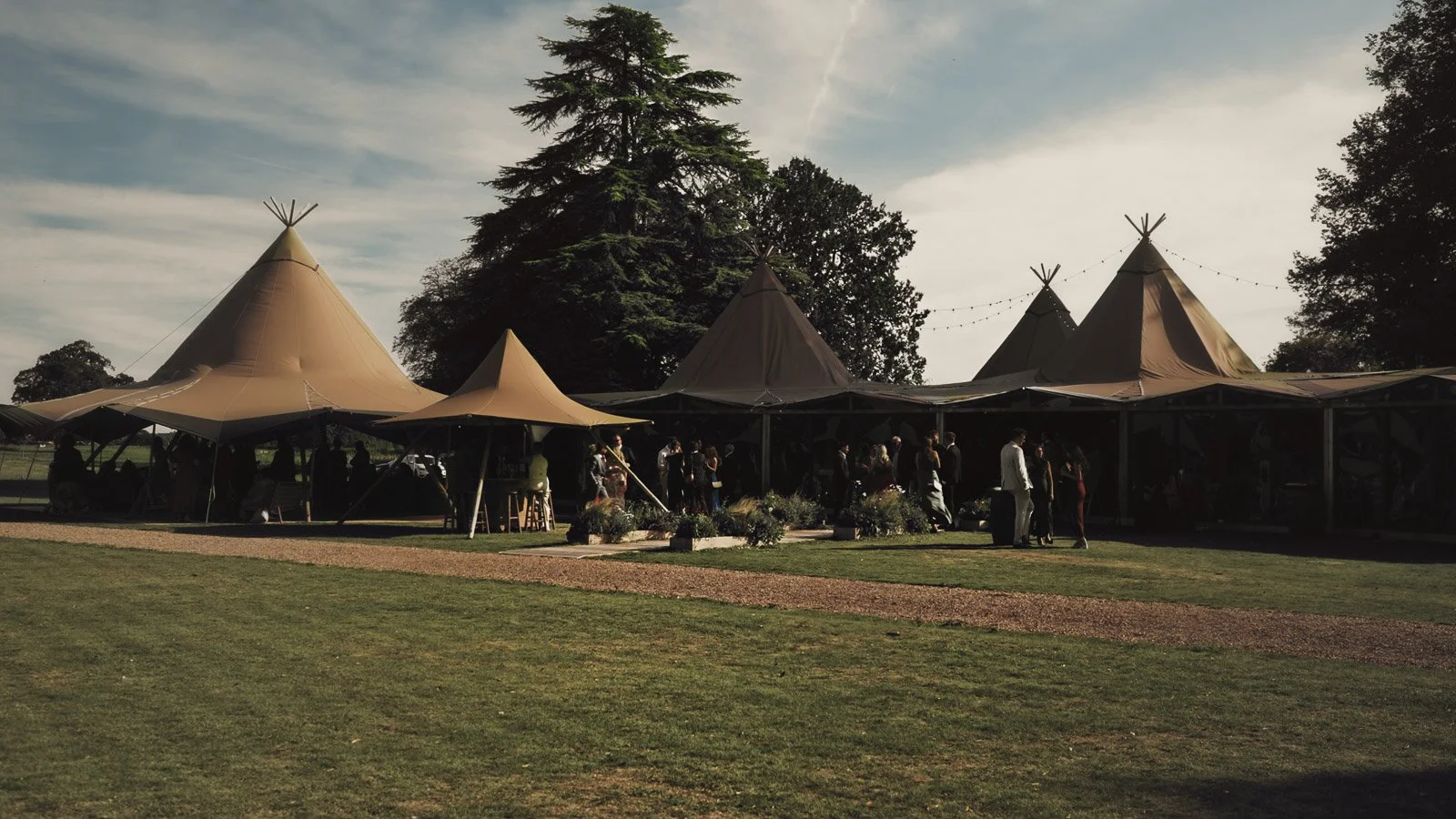 The exterior of a marquee setup at dusk during a colourful riverside wedding.