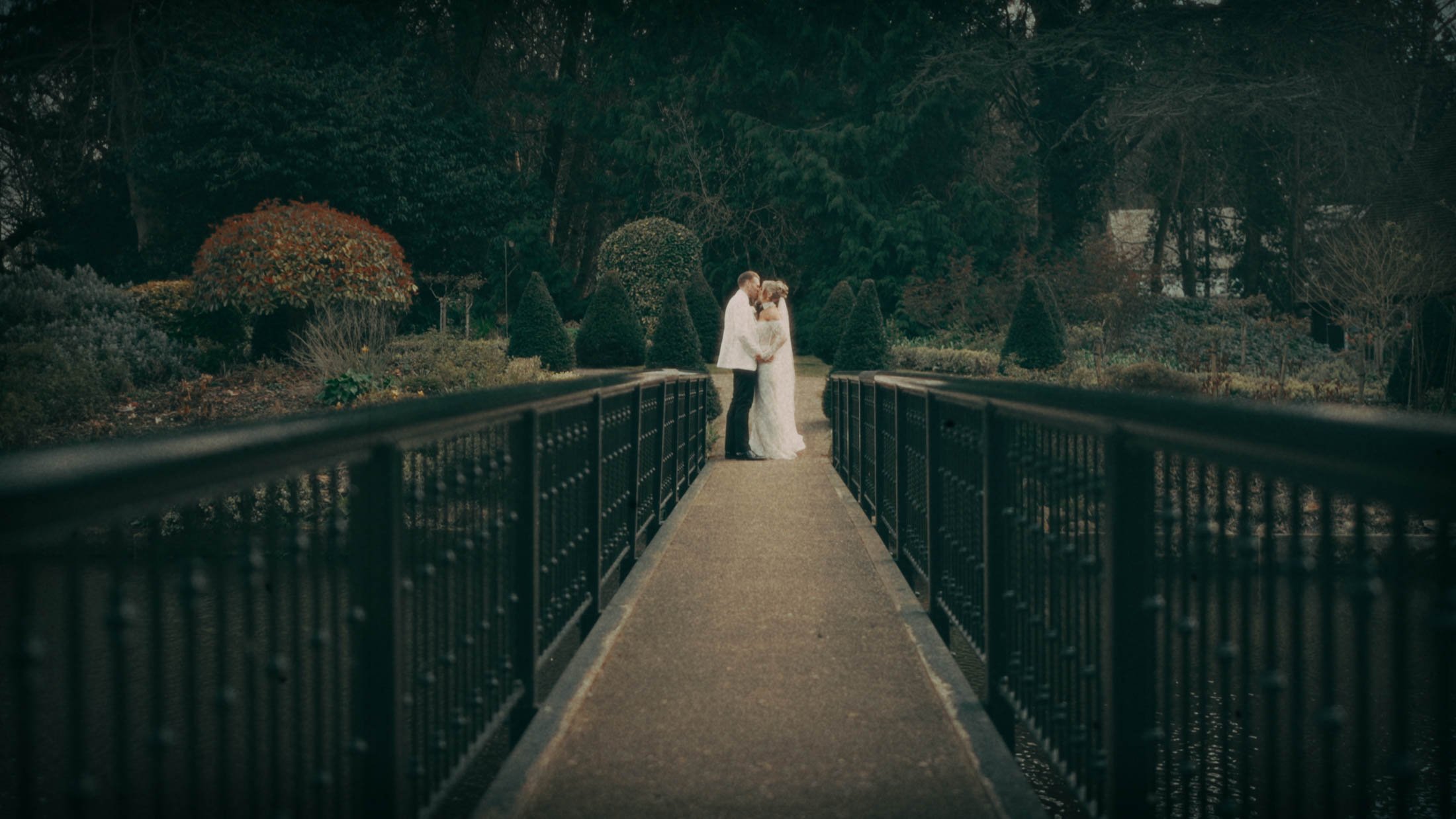 A super 8mm emulation shot of a couple on a bridge at The Orangery Maidstone, part of an intro sequence from their storytelling wedding film.