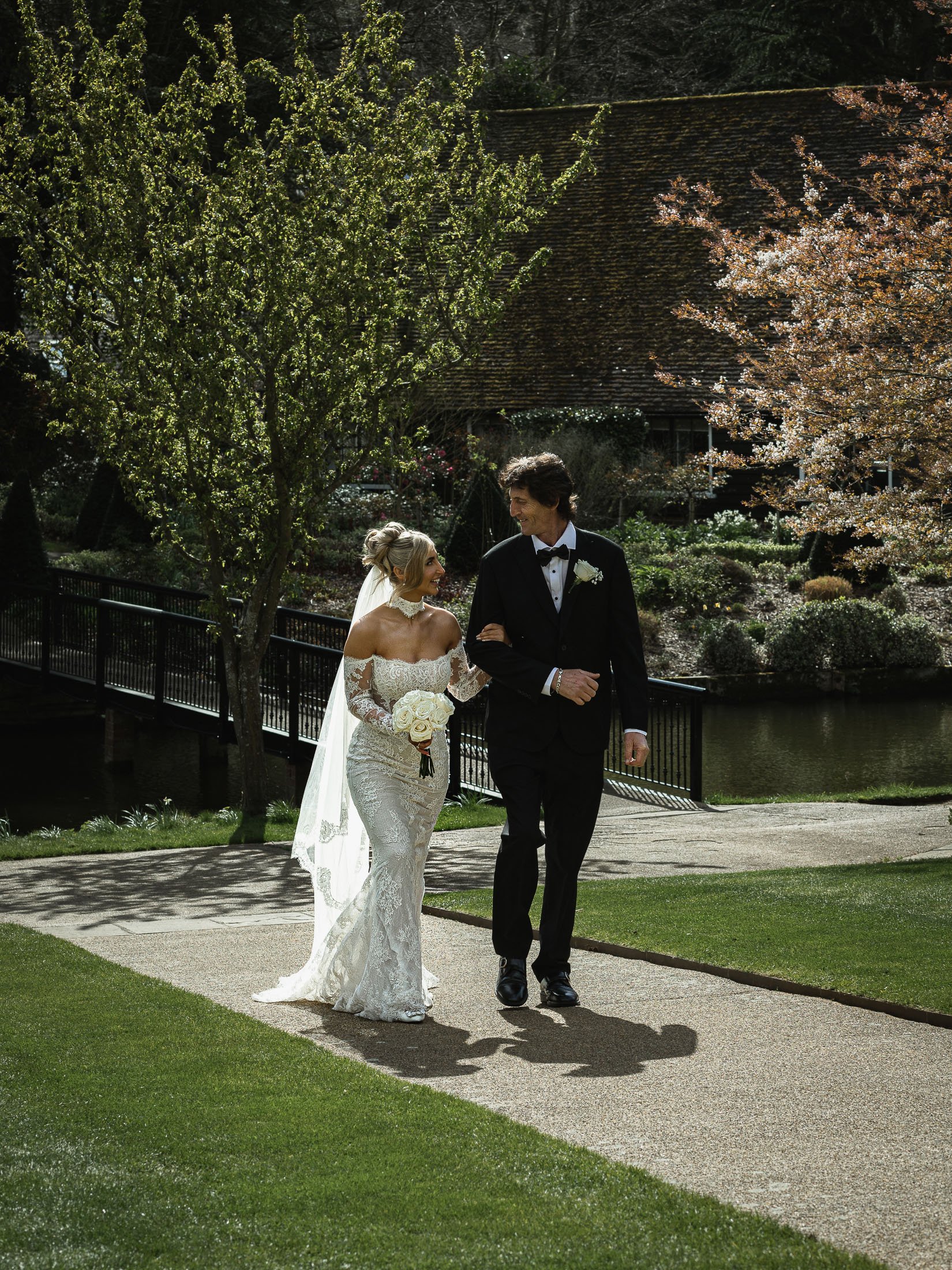 A bride walks arm-in-arm with her Father towards an indoor wedding ceremony at The Orangery Maidstone.