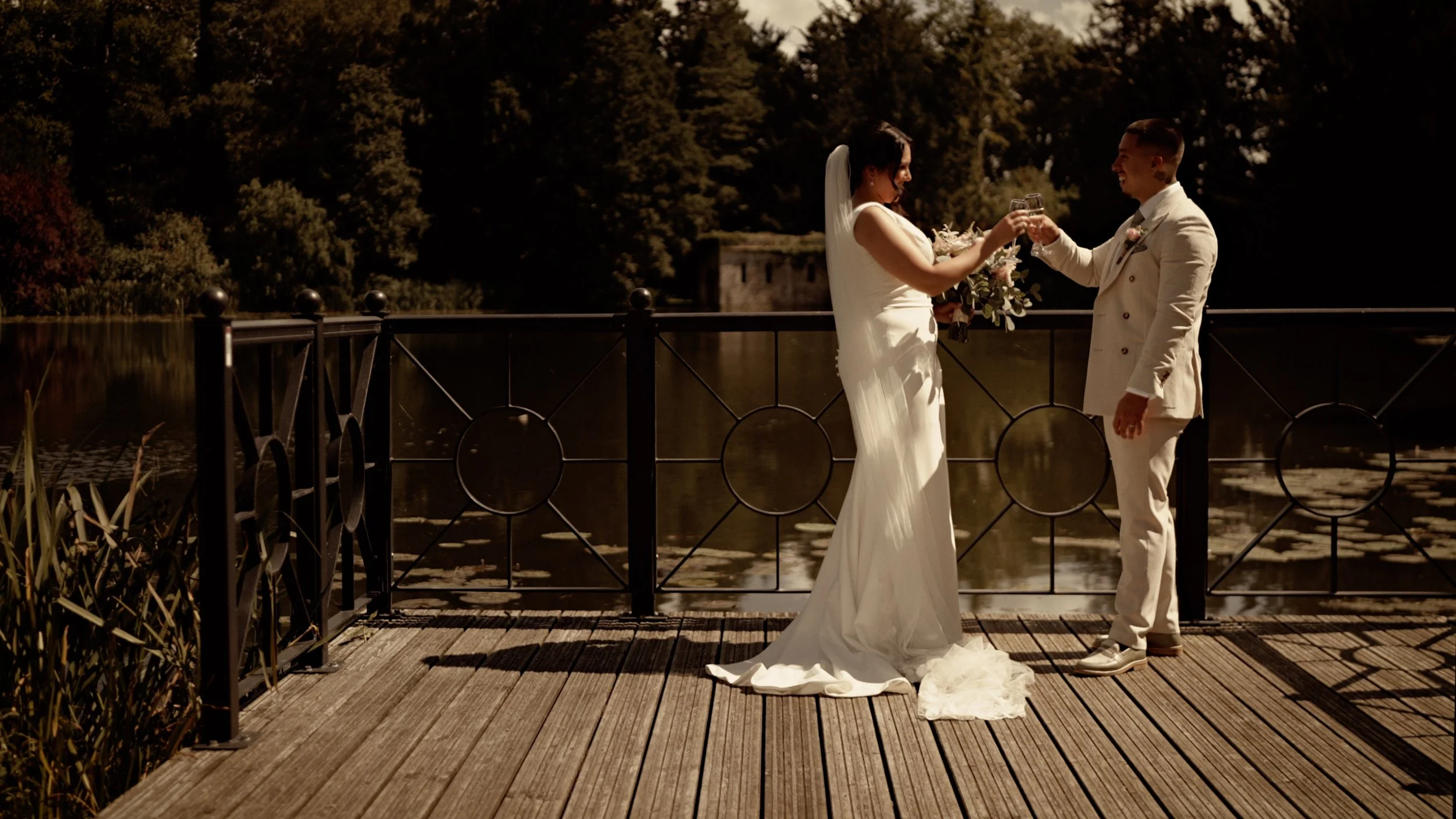 Bride and groom toasting by the lake at The Orangery Maidstone after their wedding ceremony