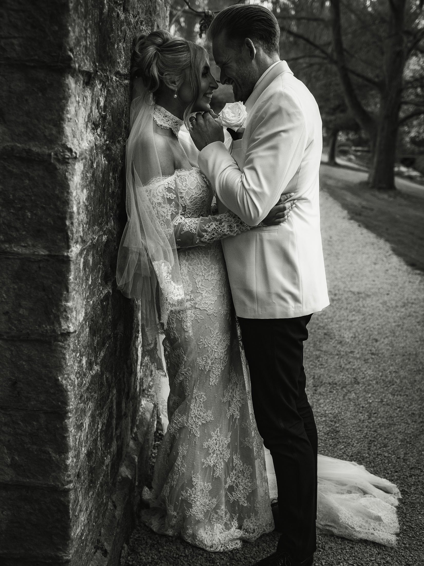 Full length editorial wedding photography and videography portrait of a bride and groom in white tuxedo by the lake at The orangery Maidstone.