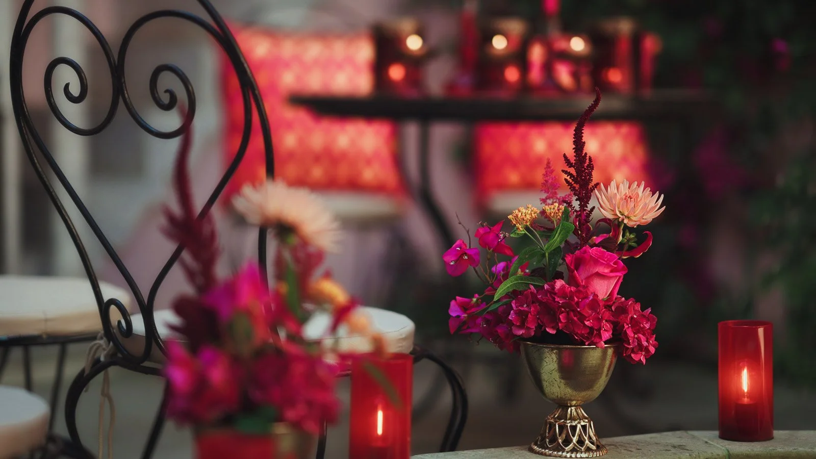 Bright pink and red floral arrangements sitting in a courtyard at an outdoor wedding ceremony in Kent.