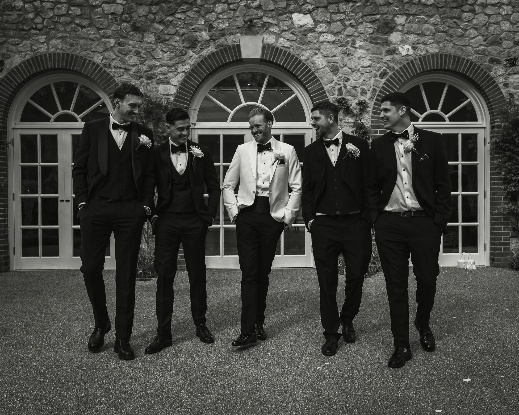 Wedding photography and videography in an editorial style capture a groom in white tuxedo with his groomsmen in black tie at The Orangery Maidstone.