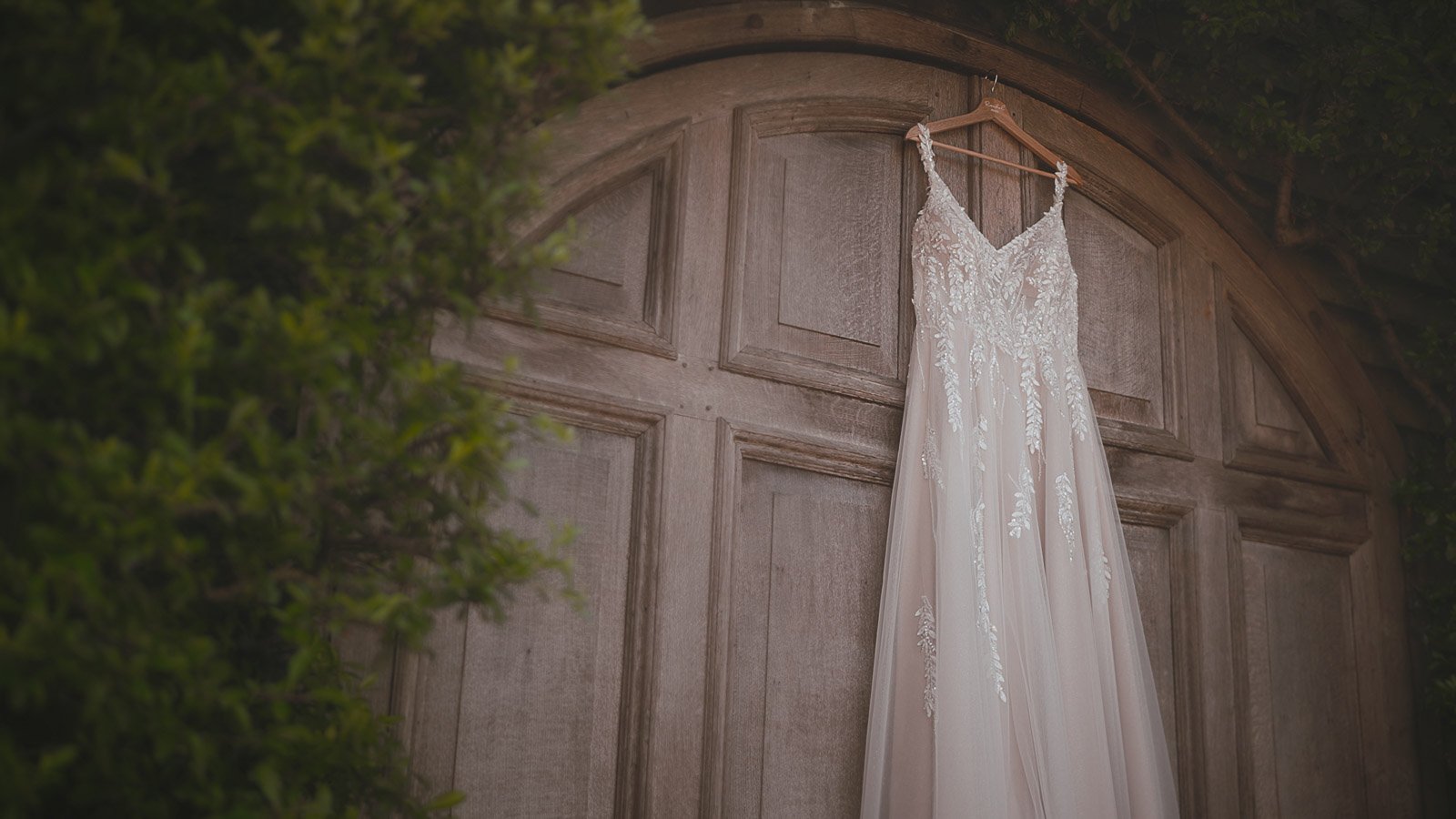Close-up of the bride’s dress hanging above the famous wooden barn doors at Winters Barns in Kent.