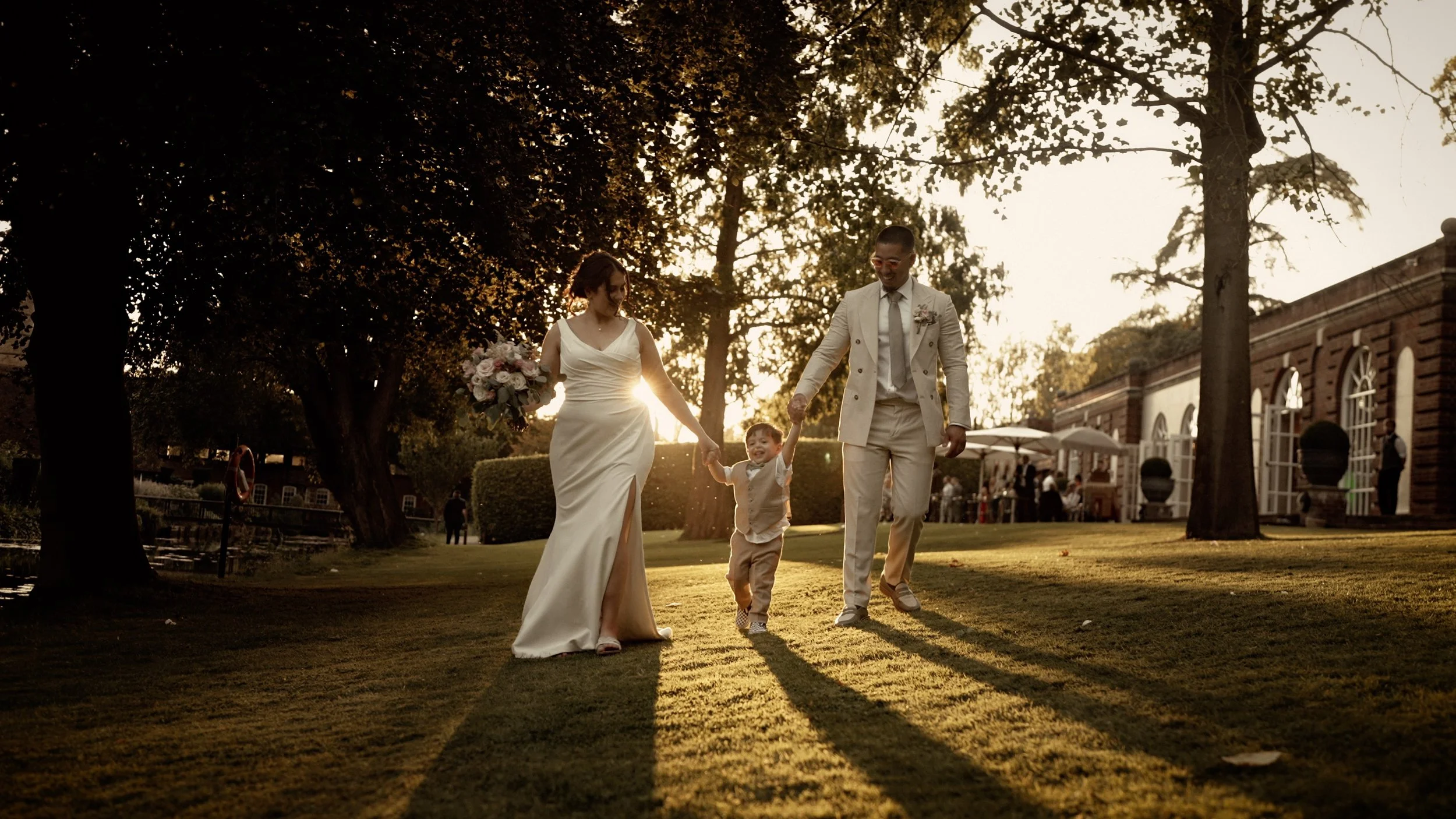 Bride and groom walk through the grounds at The Orangery Maidstone following a lakeside ceremony