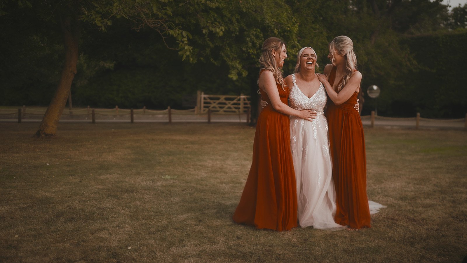 The bride and bridesmaids laugh in an open field in the grounds of Winters Barns, Kent