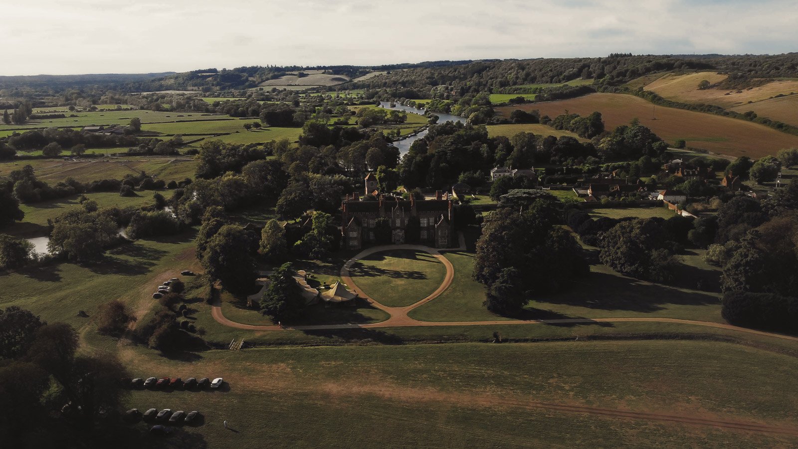 An aerial view over an Oxfordshire Estate (Mapledurham Estate) during a colourful riverside wedding day.