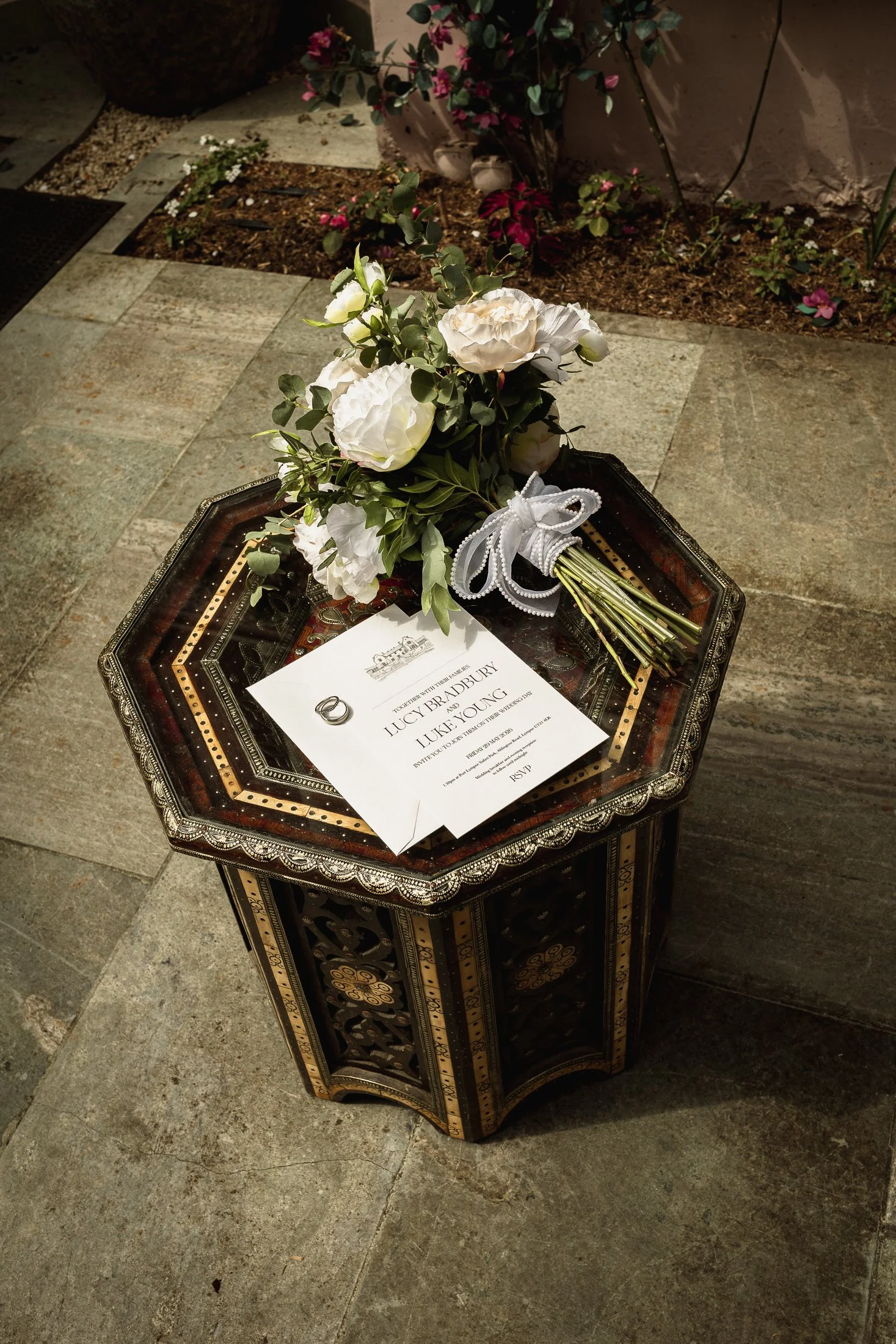 Bridal details, flowers, rings and bouquet on an ornamental table in the Moroccan Courtyard at port Lympne.