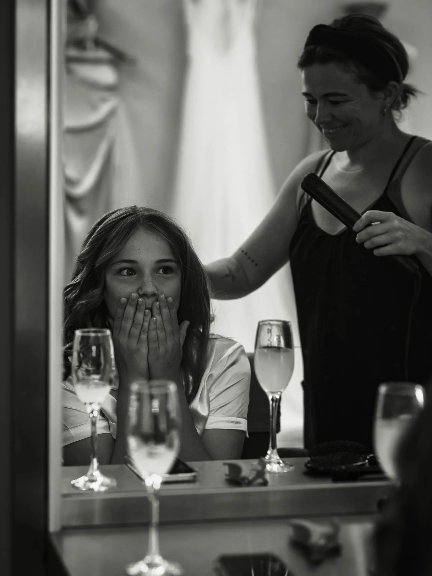 A classic and timeless black and white wedding photograph showing a bridesmaids reaction to her hair and make up in the reflection of a mirror. Captured from Winters Barns in Kent.