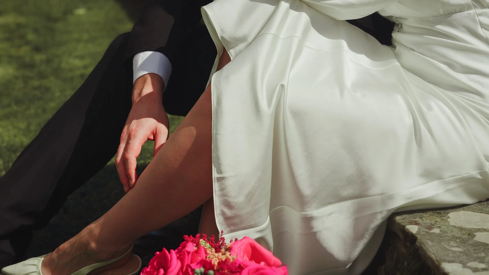 The grooms hand rests on the leg of his bride in this romantic moment, framed for an editorial wedding film.