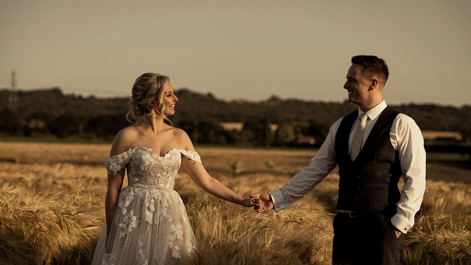 A bride and groom look at each other during golden hour in a Cooling Castle Barn wedding film.