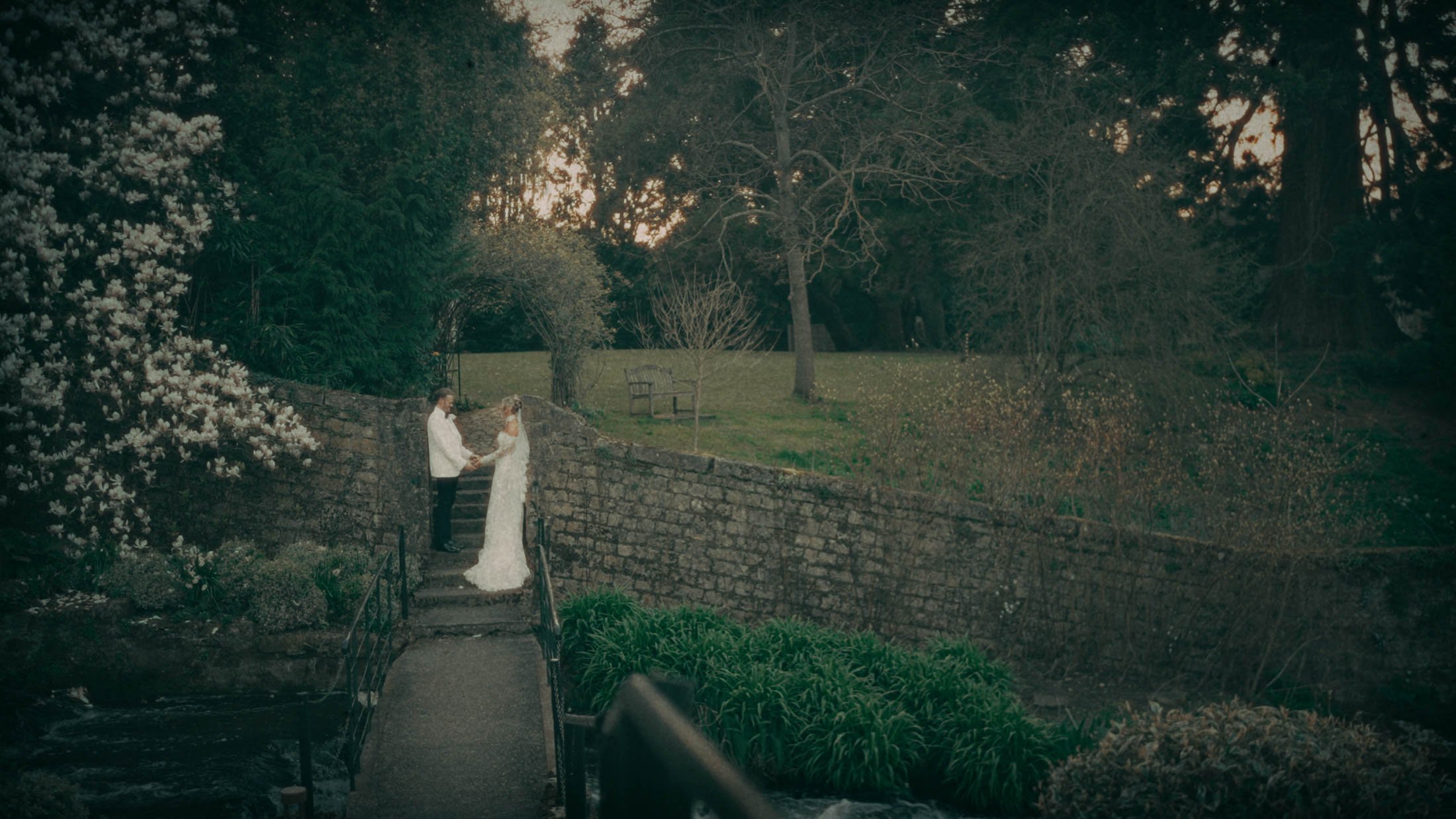 A super-wide shot of a couple stood by a river during their wedding day, captured as part of their storytelling wedding film.