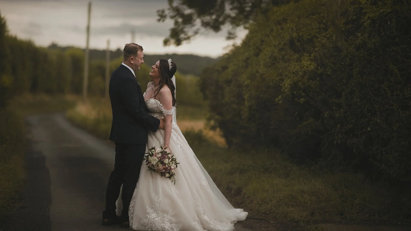 A bride and groom laugh during an editorial couple portraits filmed at golden hour near Cooling Castle Barn