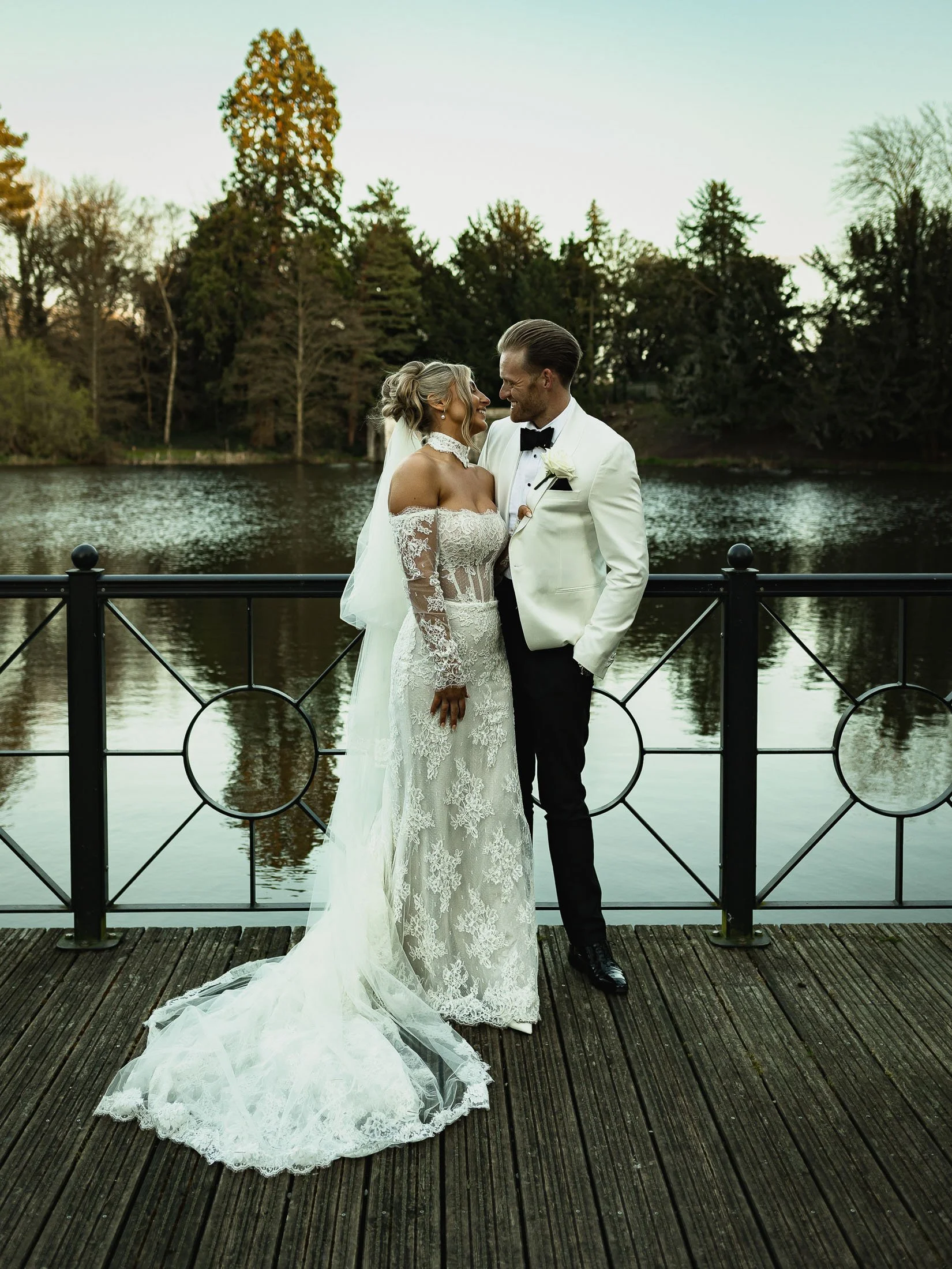 A couple pose together by the lake at The Orangery Maidstone during their black-tie wedding day.