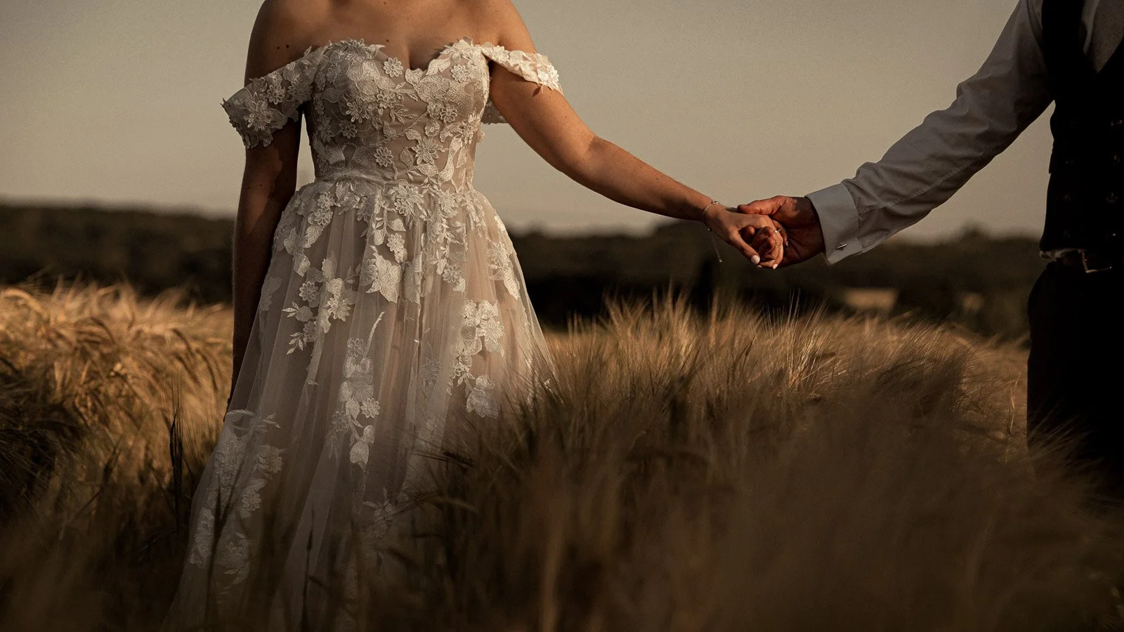 Intricate details of a brides dress at sunset in a Cooling Castle Barn wedding film.