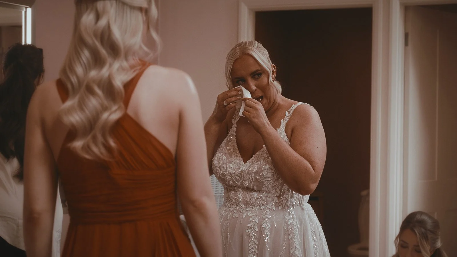 A highly emotional bride wipes tears from her eyes during bridal preparations at Winters Barns