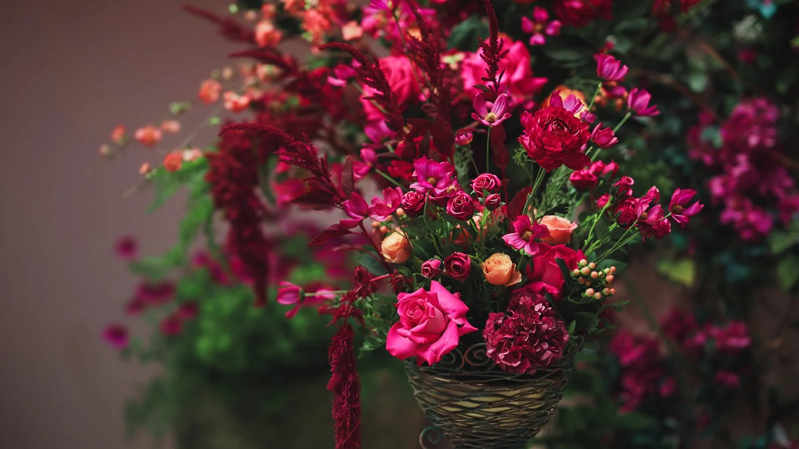 Bright pink and red floral arrangement with deep tones from a courtyard wedding.