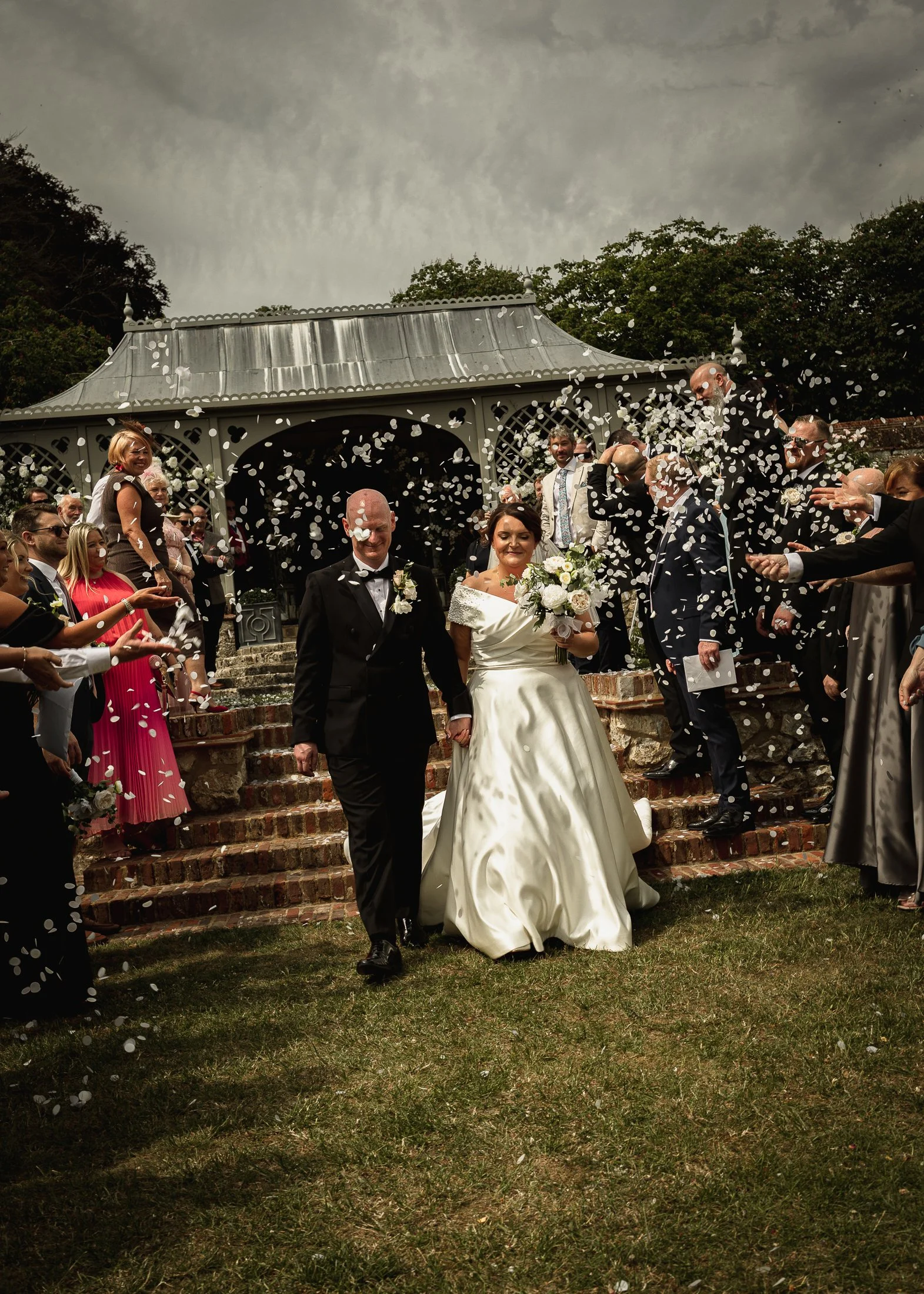 Lucy and Luke exit their wedding ceremony at Port Lympne Hotel & Reserve as guests throw confetti over them.