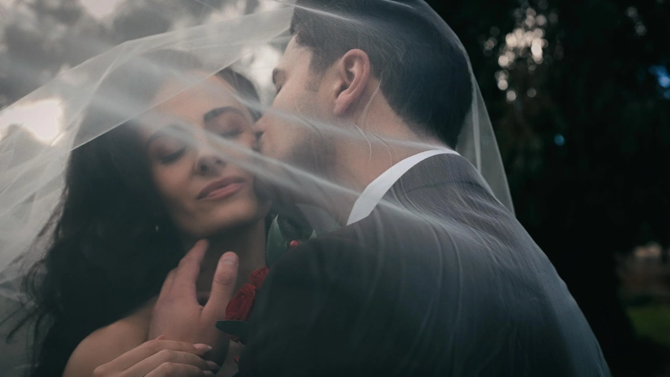 A bride and groom stand underneath a cathedral veil at Elmore Court.