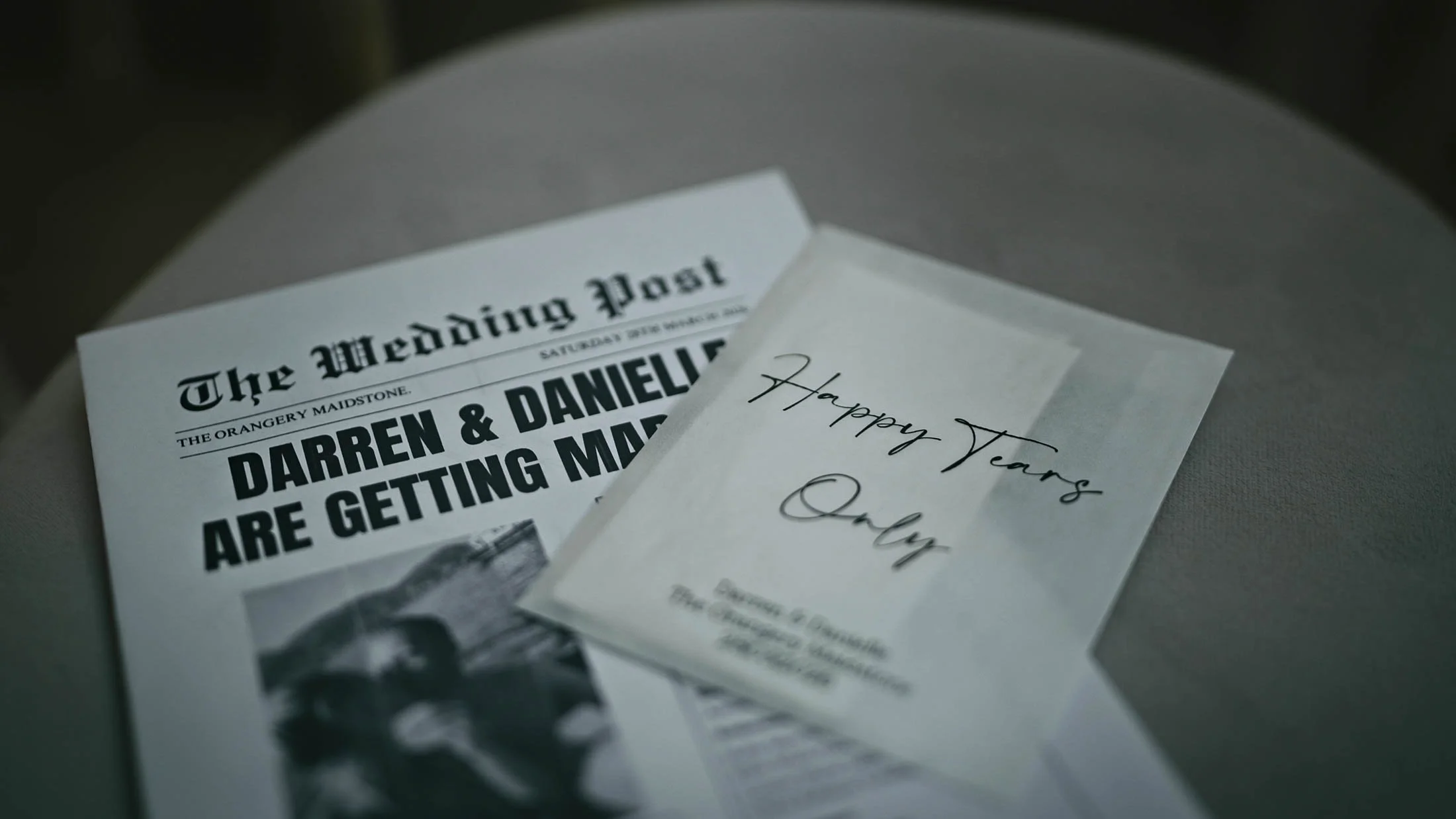 A details shot from a storytelling wedding film in the UK, showing a wedding day newspaper and tissues on a chair during the indoor ceremony.