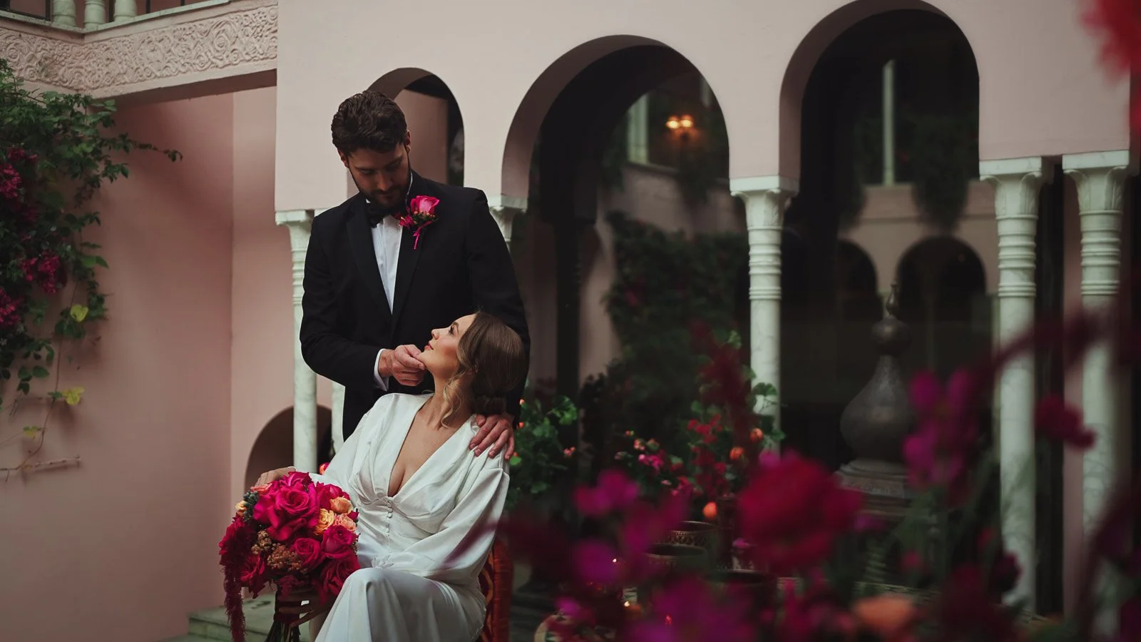 Bride and groom portrait with bold palette kept elegant through composition, with courtyard archways in the background.
