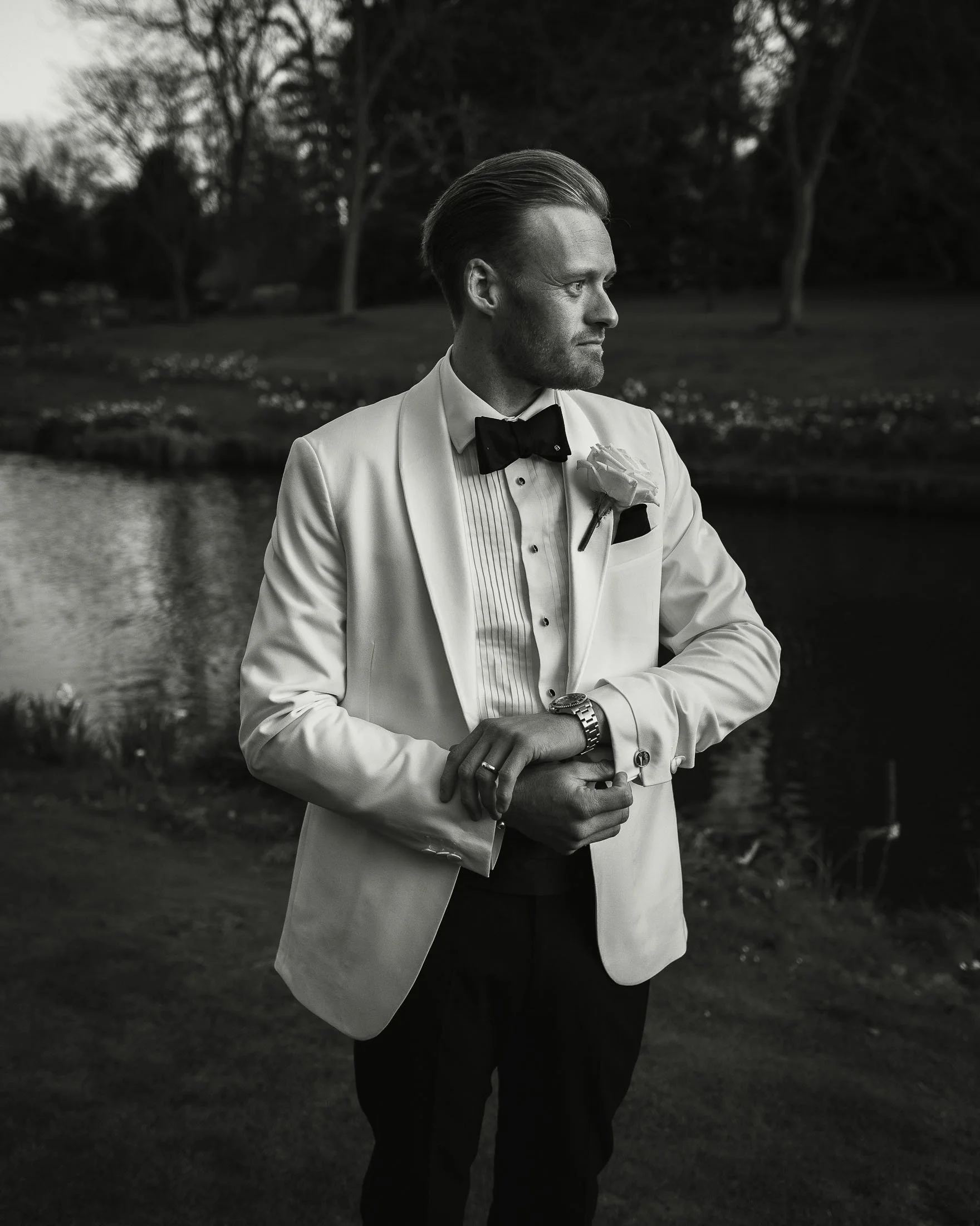 Black and white portrait image of a groom in white tuxedo at The orangery Maidstone, Kent.