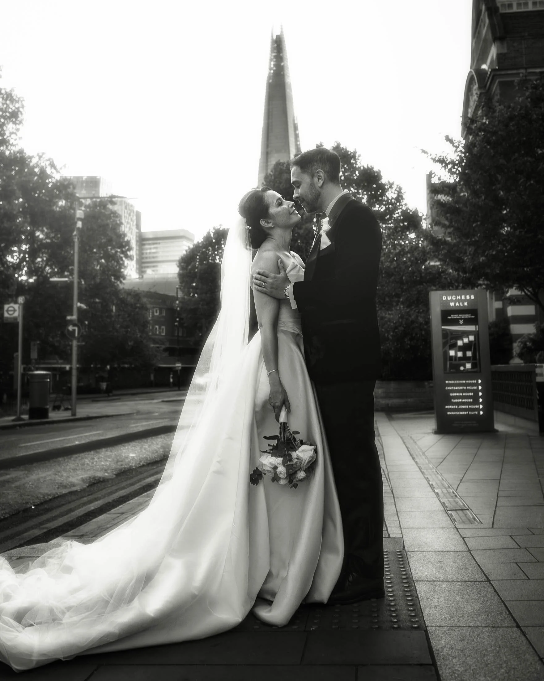 An editorial London wedding photograph showing a bride and groom embracing each other with The Shard in the background. Part of a black tie London wedding photography and videography gallery.