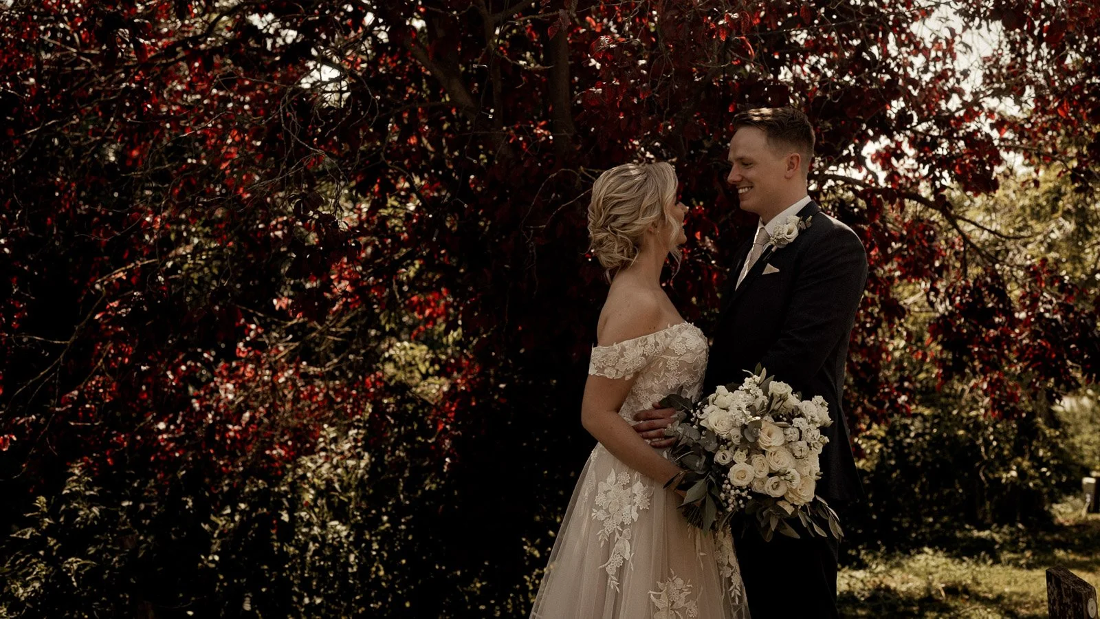 A bride and groom stand together in the grounds of Cooling castle Barn during their cinematic wedding film.