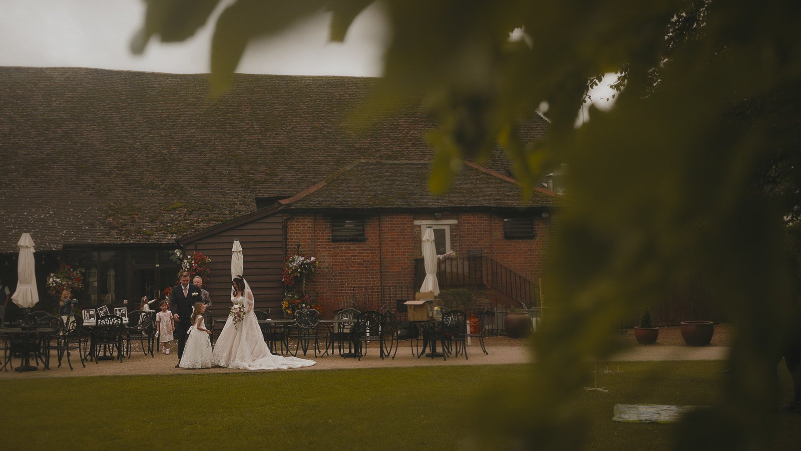 Guests talk on the lawn during an outdoor wedding reception at Cooling Castle Barn, Kent.
