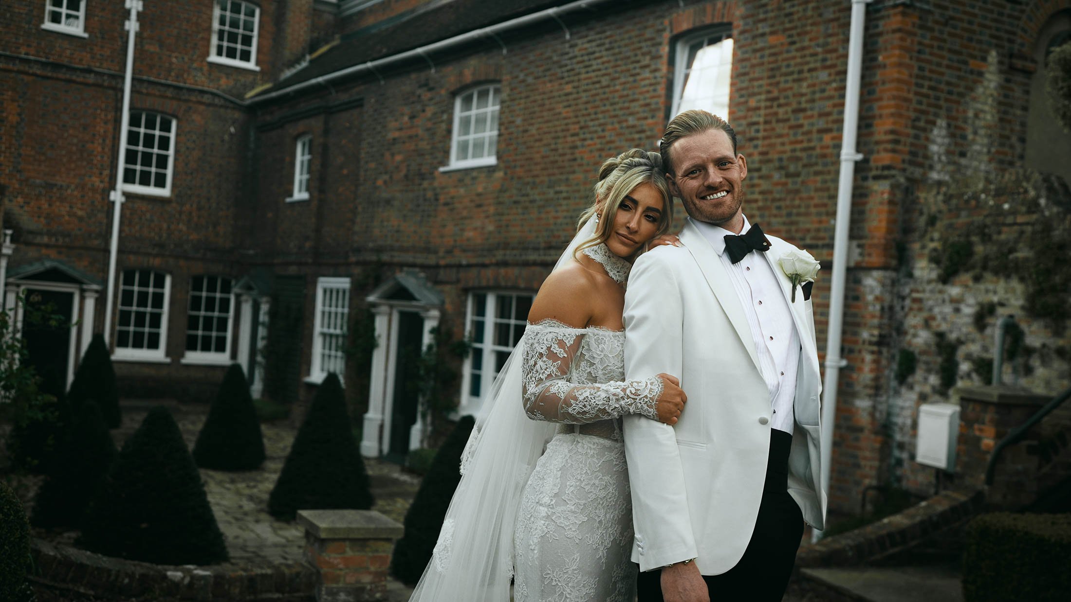 A bride and groom smiling together during their cinematic couple portrait session on their black-tie wedding day.