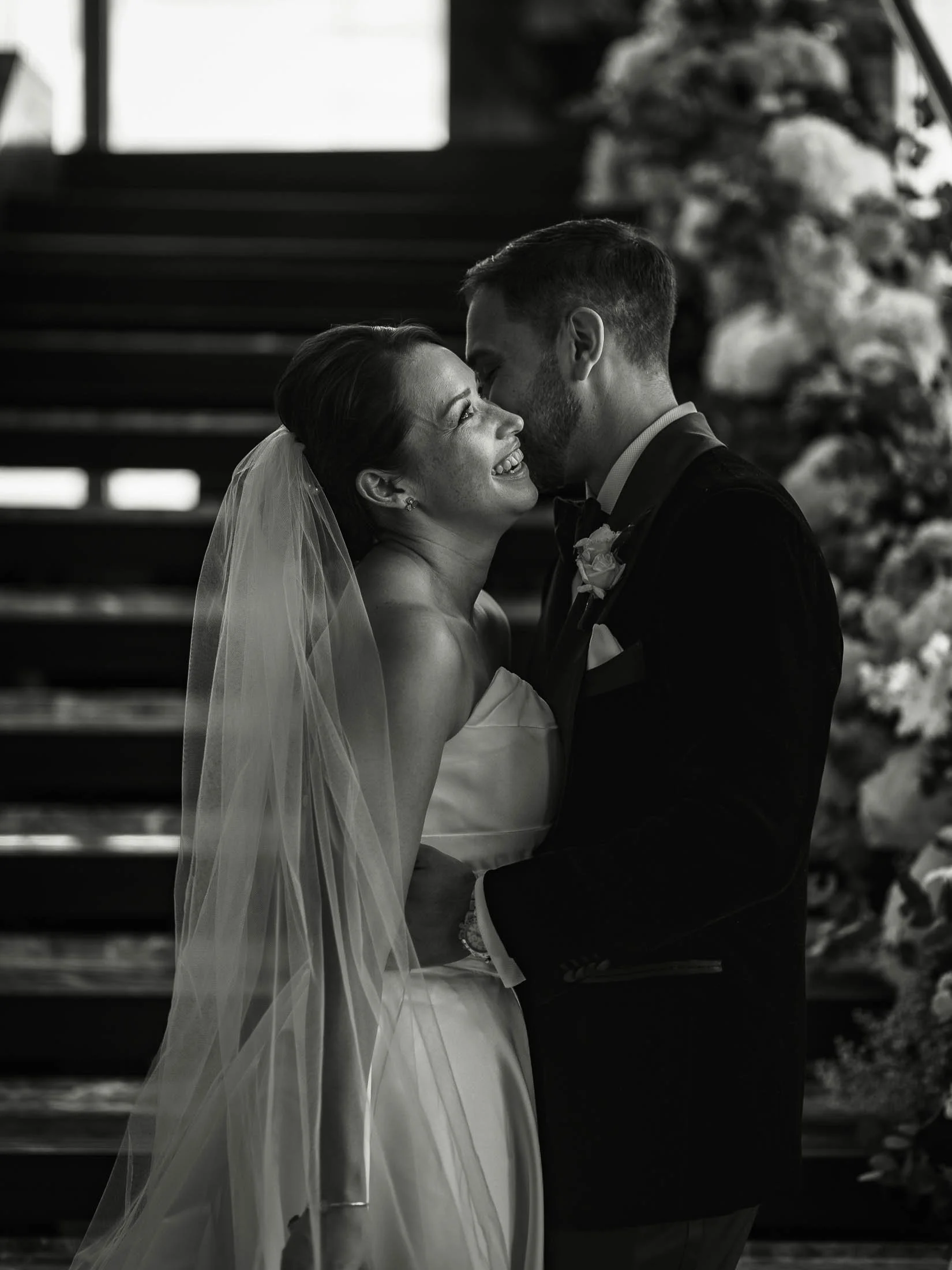 A bride and groom laugh together by the staircase of the Shangri-La hotel at The Shard on their formal black tie wedding day.