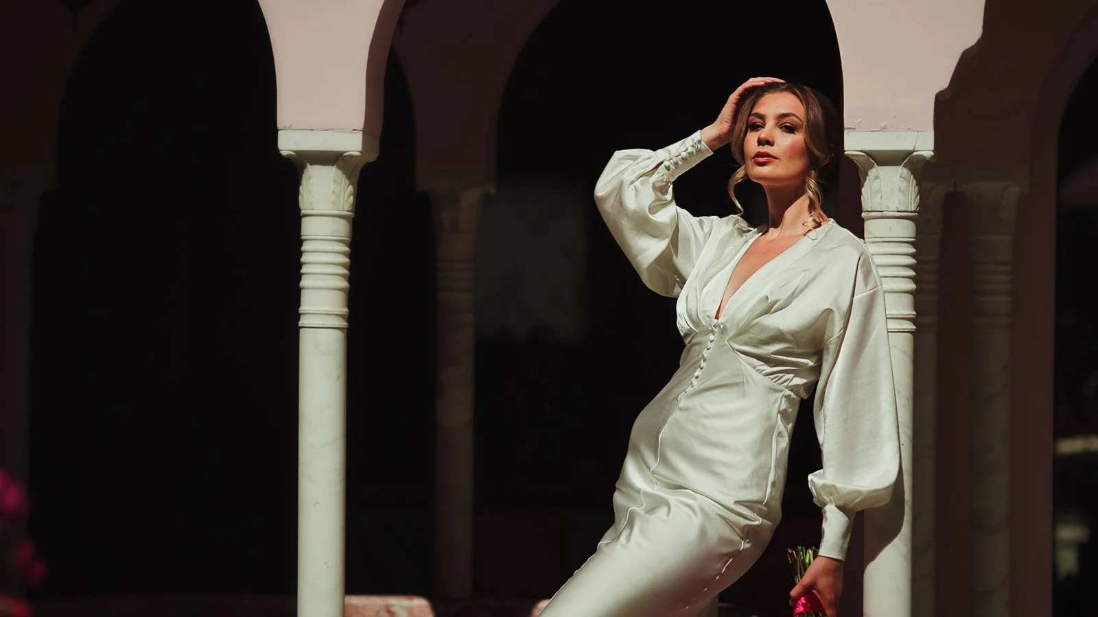 Bridal portrait with clean dress styling and saturated floral backdrop with arches.