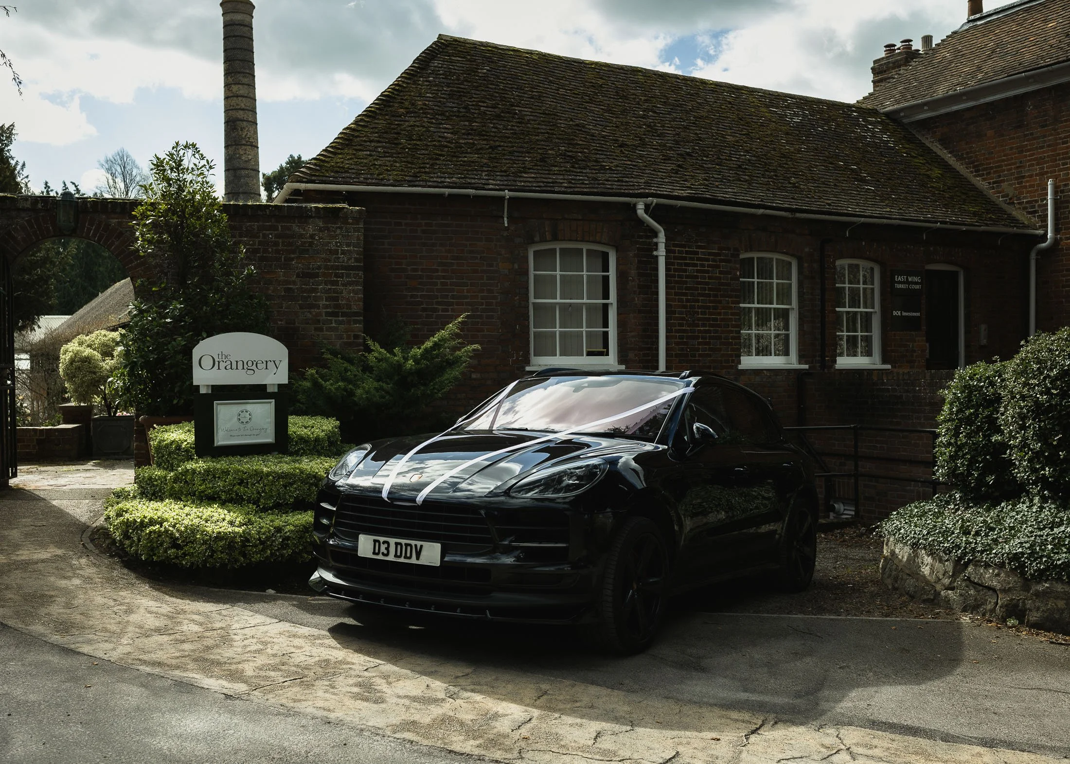 A luxury wedding car with ribbons is parked at the entrance to The Orangery Maidstone in Kent.