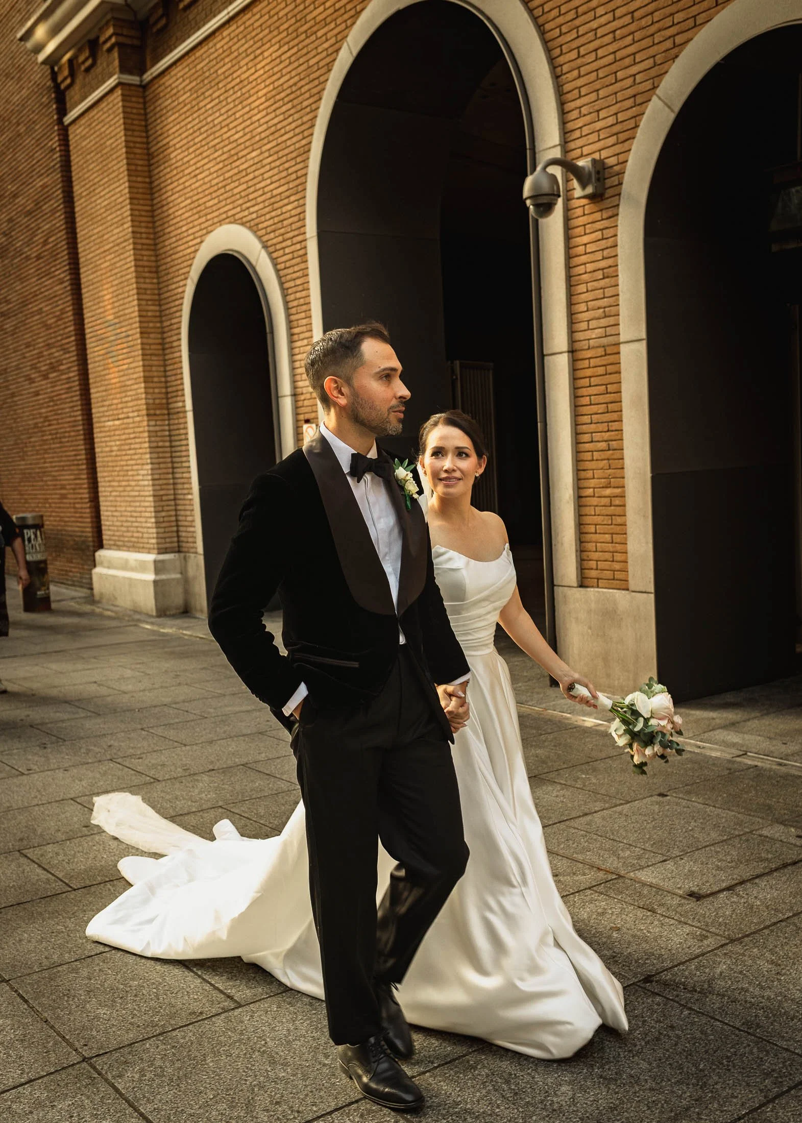 A couple walk through London Bridge on their black tie wedding day.